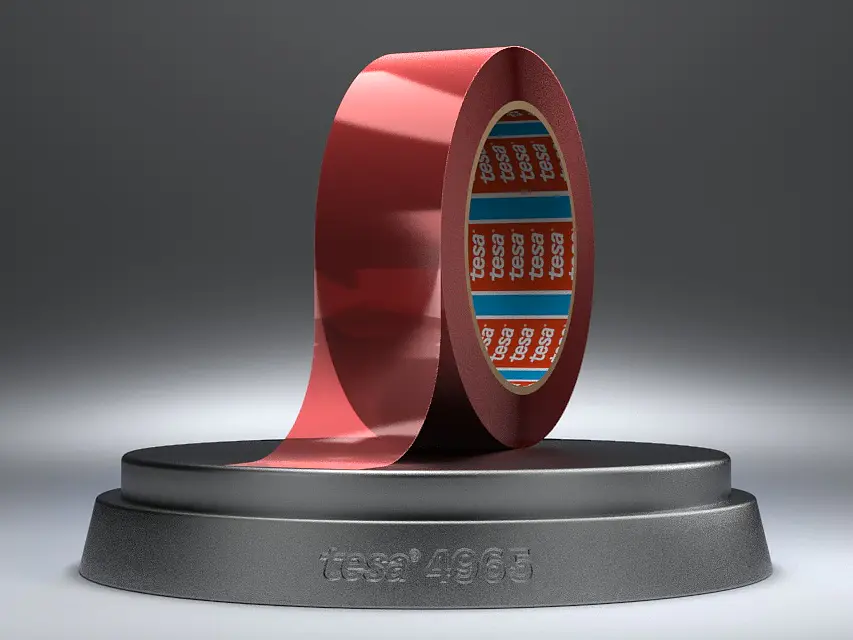 A roll of shiny red tesa tape is displayed upright on a round, dark grey stand with 1968 engraved on it. The inner core of the tesa tape has a blue design with red and white text. The background is a gradient of grey. (This text has been generated by AI)