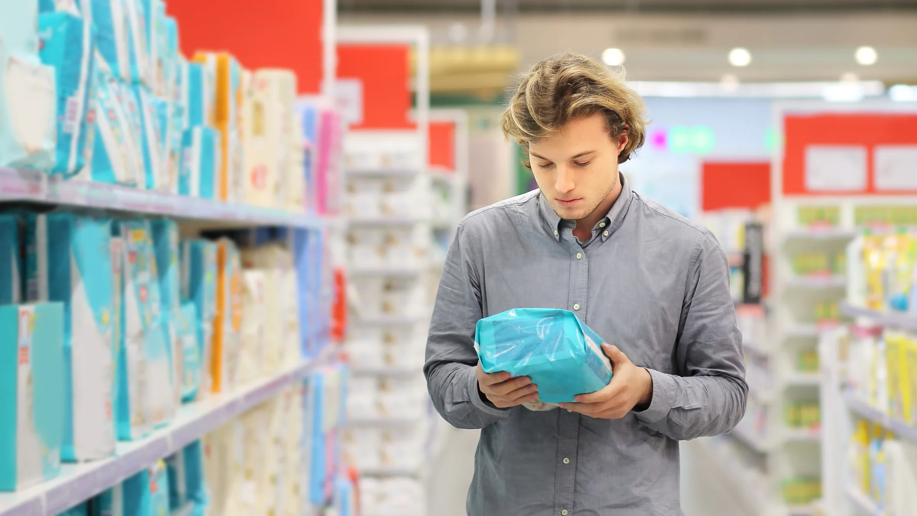 Man reading hygiene product packaging in supermarket Purchasing Hygiene Products