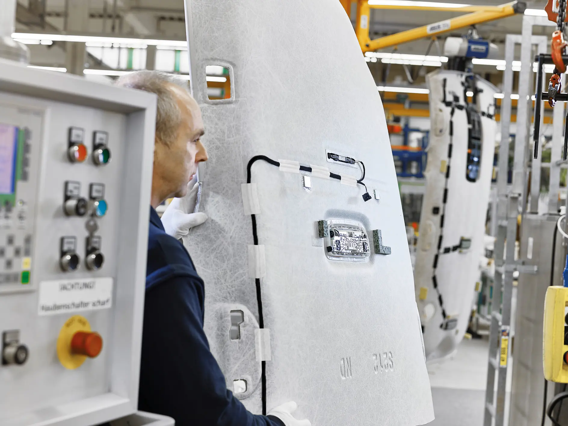 tesa worker operating machinery in an industrial setting with large white panels and control buttons visible indoors (This text has been generated by AI)