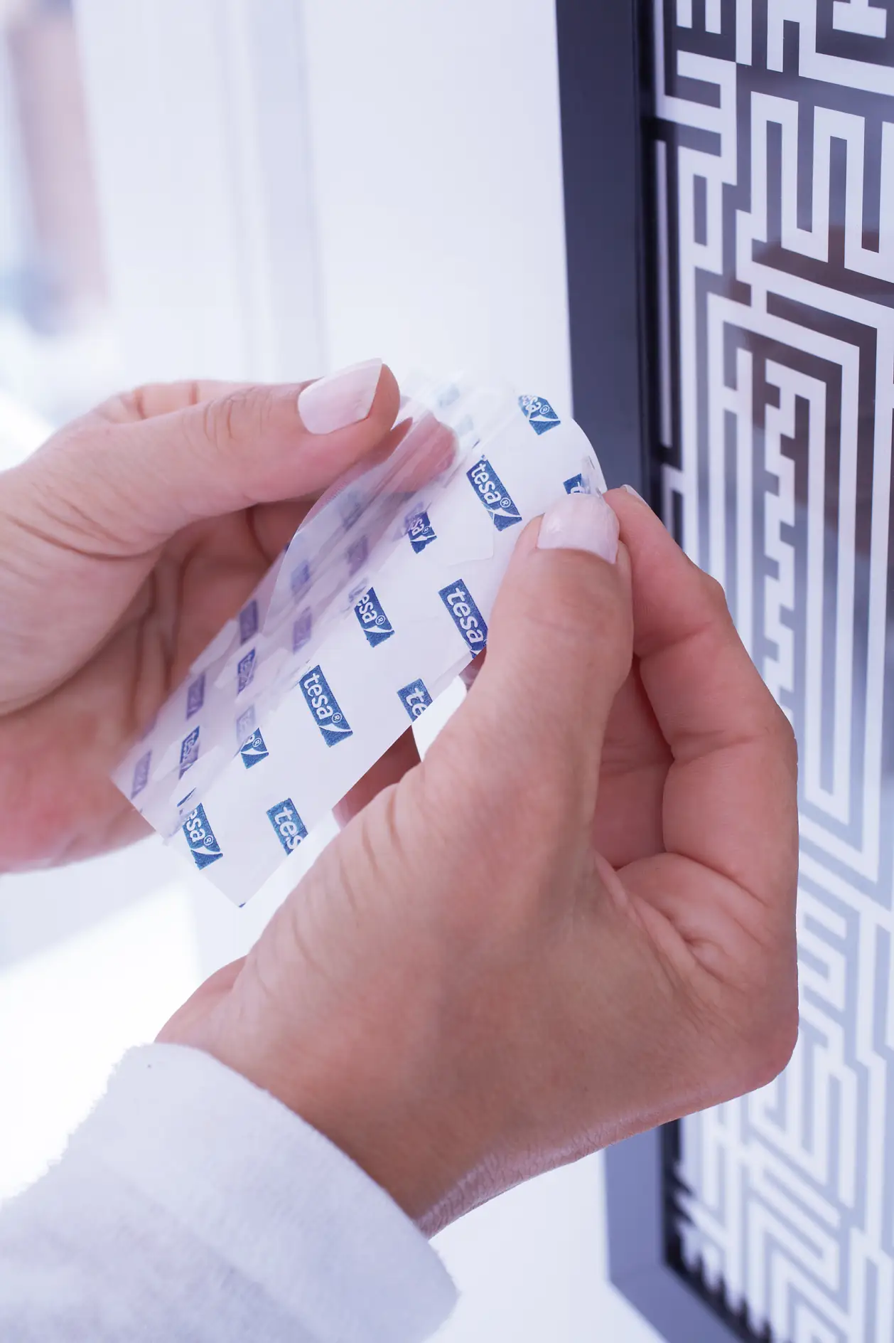 Hang-up the finished frames. Remove the protective foil from a tesa TACK® adhesive pad.