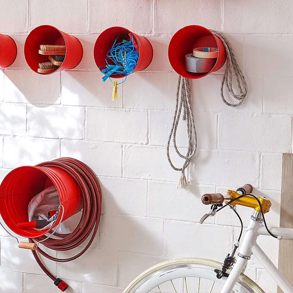 Garden hose storage made out of wall-mounted buckets
