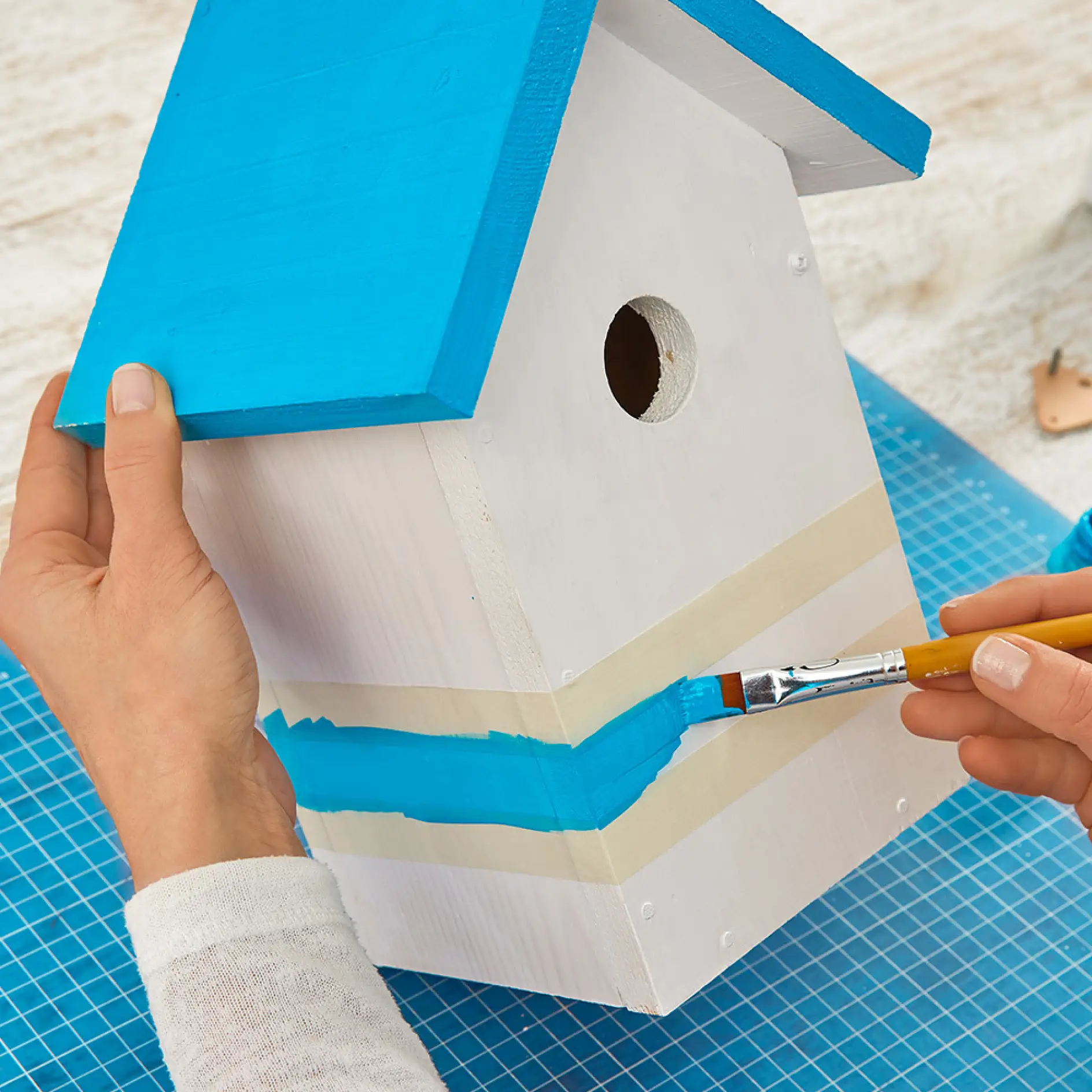 Painting a blue design while making wooden bird houses.