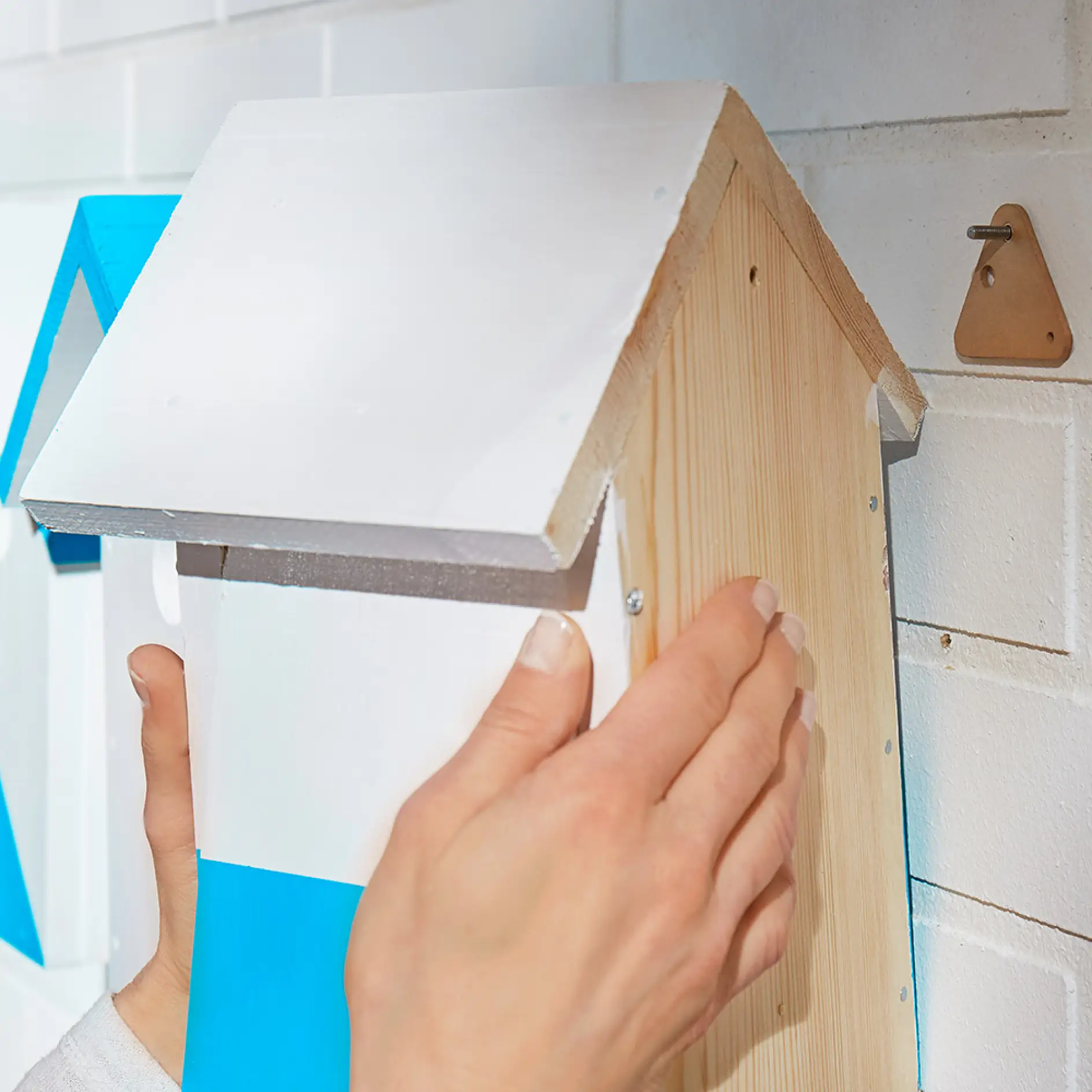 Using a tesa® adhesive screw triangular for brick & stone 10kg to wall mount a wooden bird house.