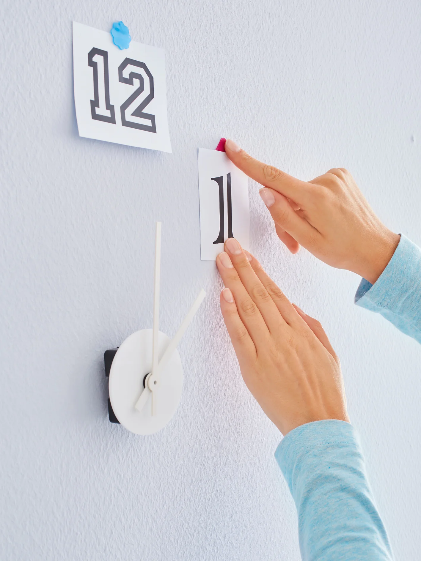 Fixing clockwork to wall. Then, arranging tesa® Tack Coloured Adhesive Pads around the clockwork.