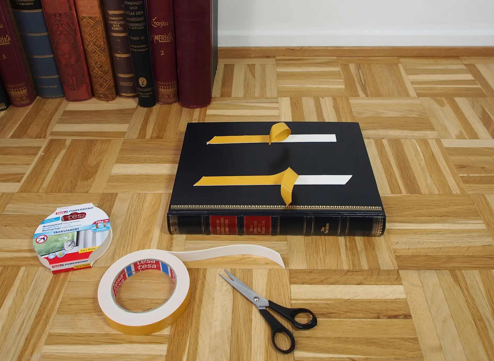 Image of book with protective film being removed from tesa® Powerbond double-sided adhesive tape.