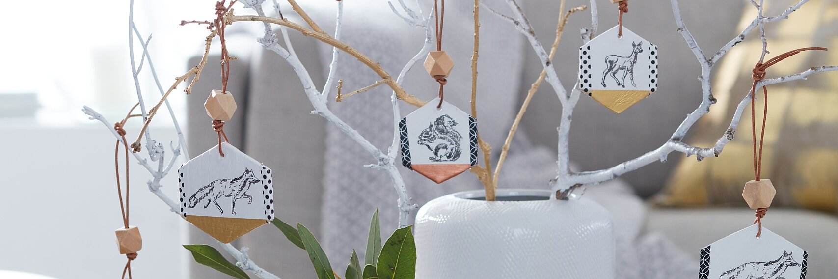 Hexagons made of air-drying modeling clay are the base for these tags. Various animals romp and roam - they are simply stamped on the tags. In order to highlight them, the bottom corners feature a metallic shimmer. On the left and on the right side, the tags are framed by a decorative border made with tesa® Deco Tape.