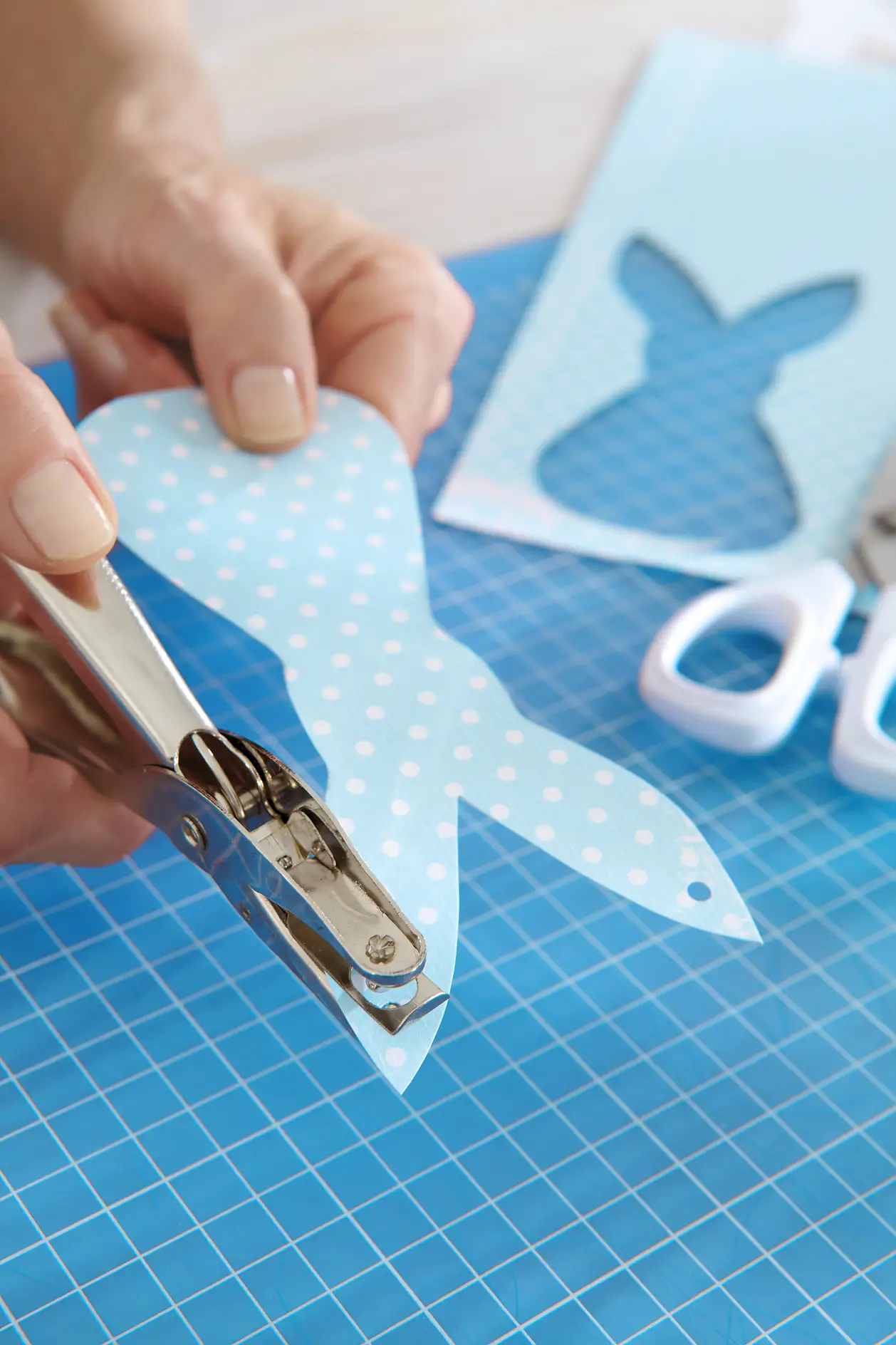 Punch a whole in the tips of both ears in the middle. String the paper rabbits on to the ribbon.