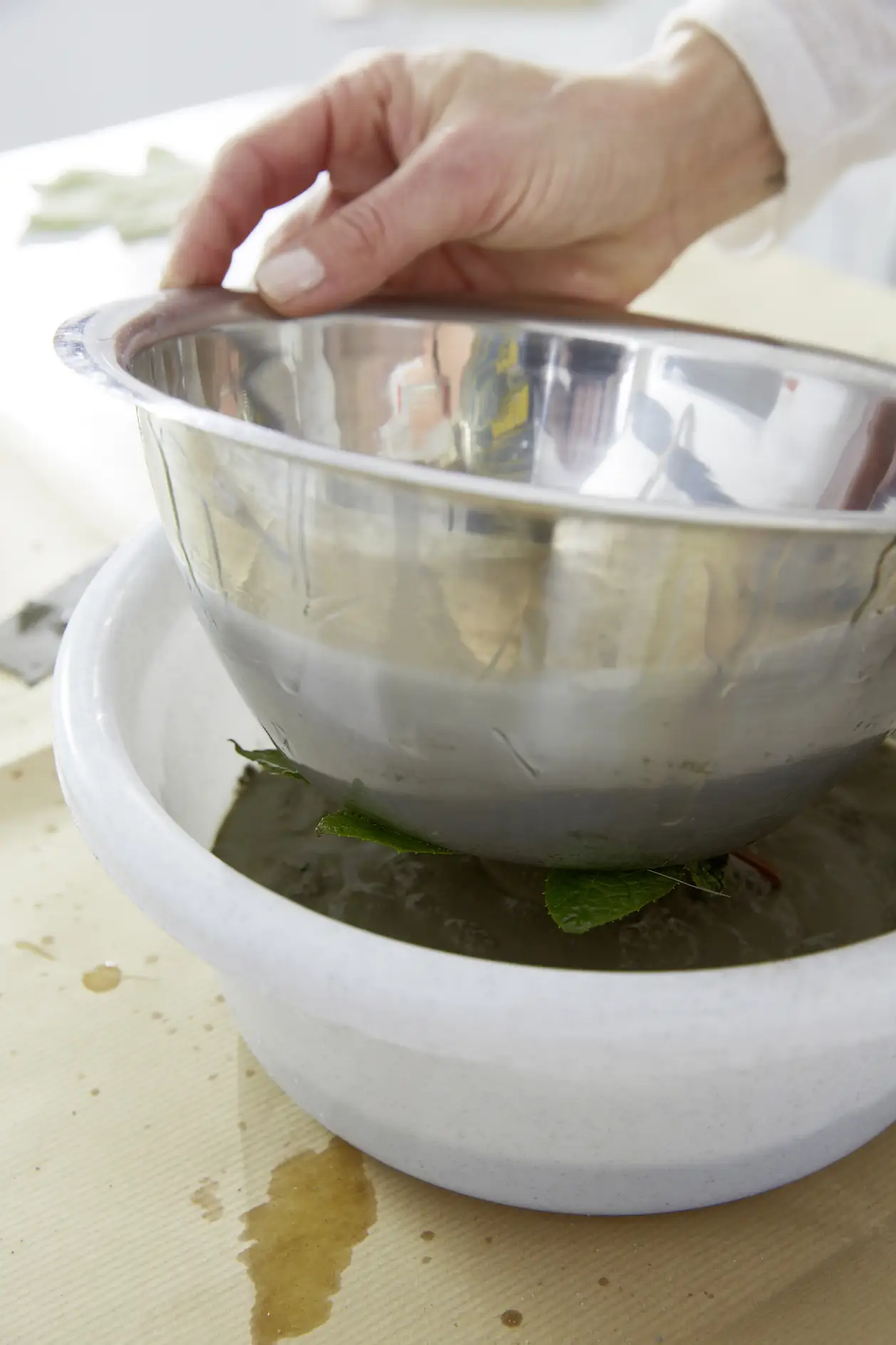 Pour the mixture into the larger bowl, place the smaller bowl with the leaf inside. Press the smaller bowl down.