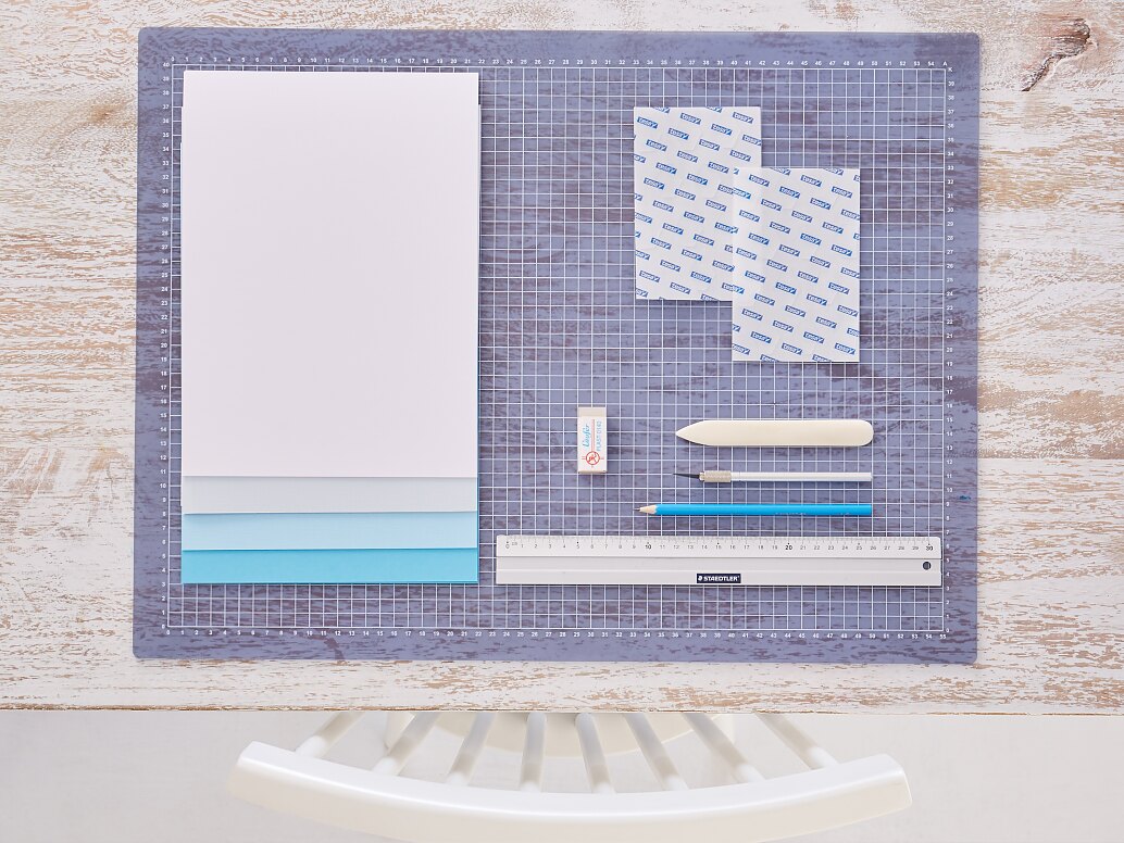 tesa trendpapier 24 / Idee 1: Wandbild / Schritt 1 Das brauchen wir: DIN-A-4-Karton in abgestuften Blautönen und Weiß, Lineal, Cutter, Bleistift, Falzbein, Radiergummi, Schneideunterlage, tesa® TACK Transparente Doppelseitige Klebepads XL