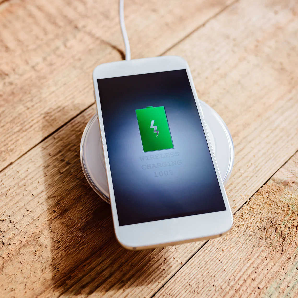 White smartphone charging on a charging pad.