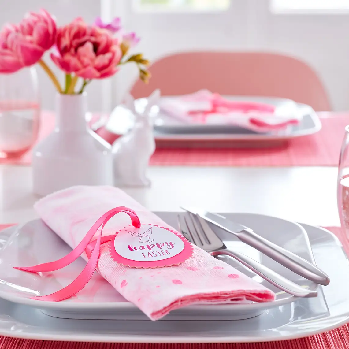Pink is the main color on this Easter table. The bunny napkin folds each wear a matching DIY napkin ring with a bunny portrait and good wishes for the spring holidays.