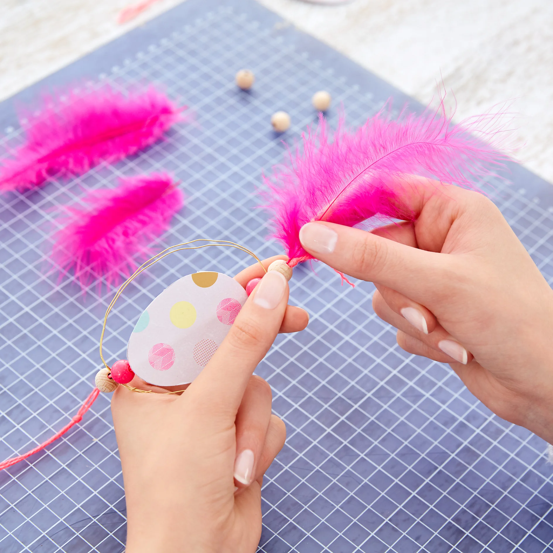 Repeat on the bottom, knot the strings right under the wooden bead. Cut off the strings (4 cm) and pull them apart until they are fringed. 
Now, insert a feather into the hole of the lower wooden bead.