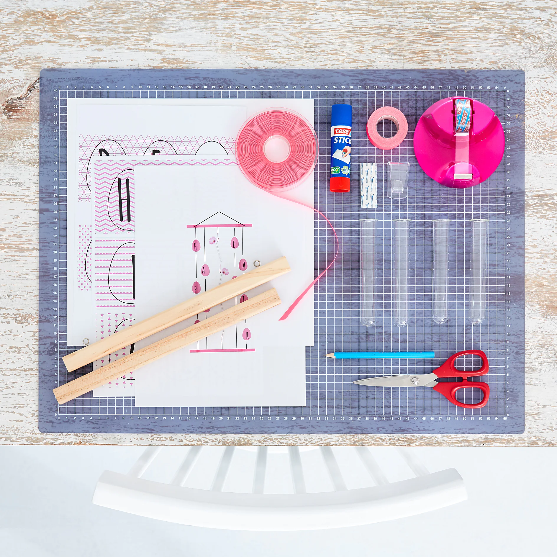 We need: 
Magnetic poster rails 30 cm, egg templates for DIY Easter decorations printed on sturdy paper, schematic drawing, white cardboard, scissors, pencil, 4 test tube vases 15 cm, 4.5 meters neon pink ribbon (6 mm wide), tesa Glue Stick ecoLogo®, tesa Extra Power® Neon Tape Pink, tesa Powerstrips® Transparent Hooks Large, tesa Easy Cut® Compact Desk dispenser + tesafilm® crystal clear