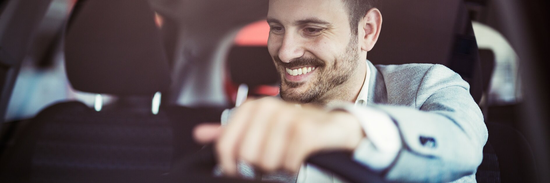 Attractive happy man driving car and smiling