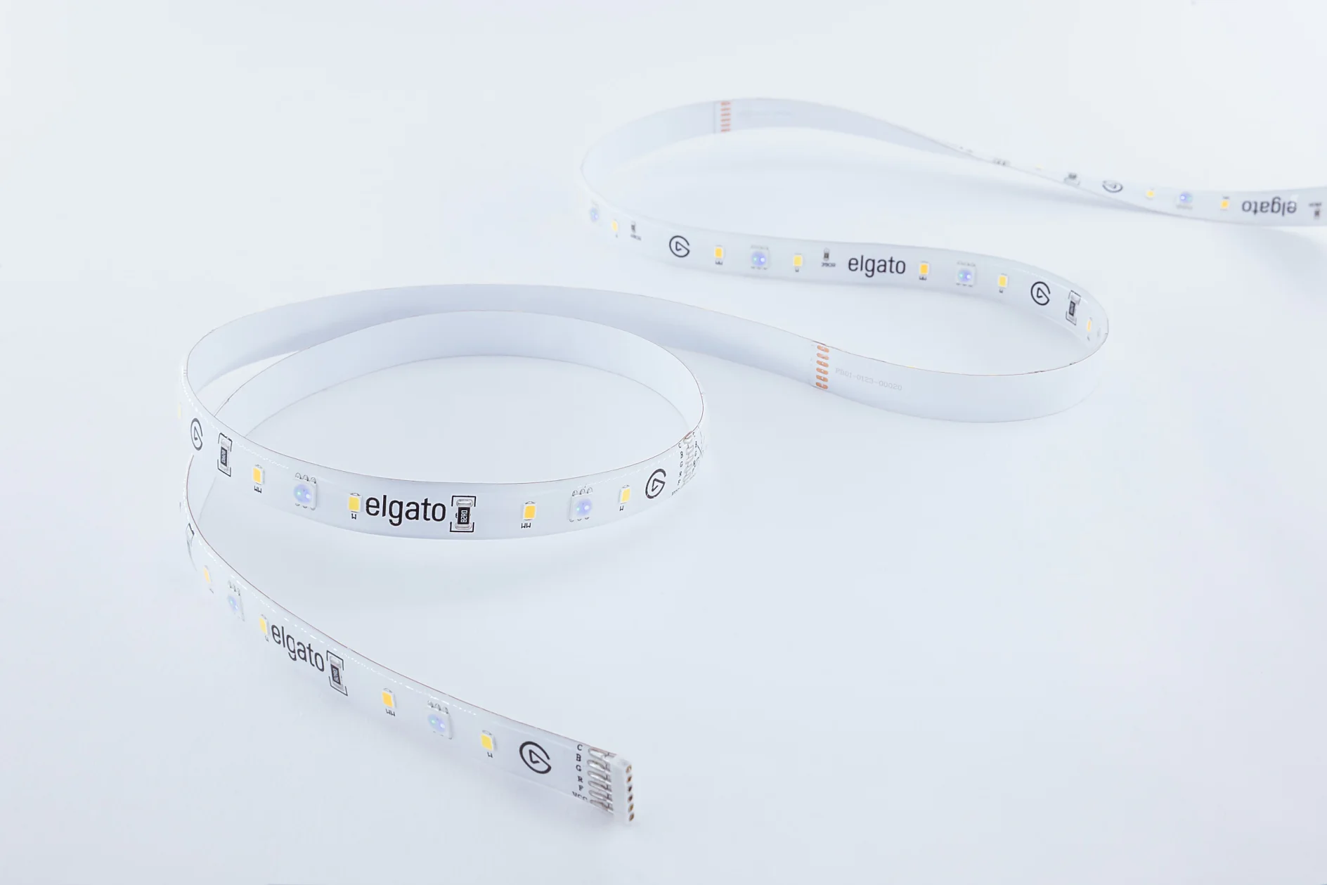A coiled LED light strip with a white background. The strip features various small LED lights and markings, including the text elgato. The components are securely attached using tesa tape for optimal performance and adherence. (This text has been generated by AI)