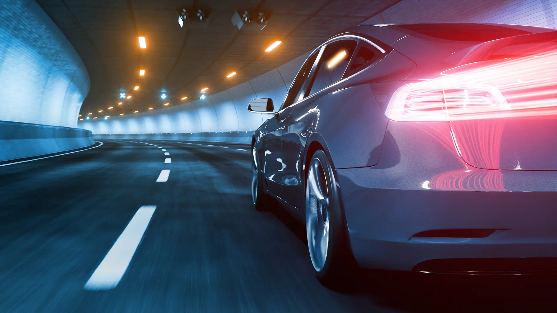 A sleek car with illuminated taillights speeds through a well-lit tunnel. The road is marked with dashed white lines, and the surrounding walls are light blue. The tunnel is equipped with overhead lights and is curving to the left. (This text has been generated by AI)
