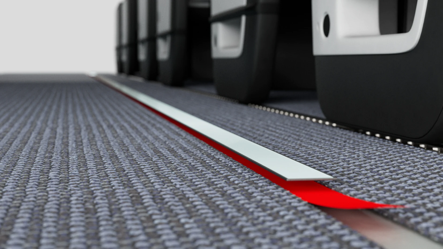 A red linear strip light is installed along the carpeted floor next to the seats on a commercial airplane. The seats have tray tables stowed on the back. The light appears to serve as an aisle marker or guide, securely fastened with tesa tape. (This text has been generated by AI)