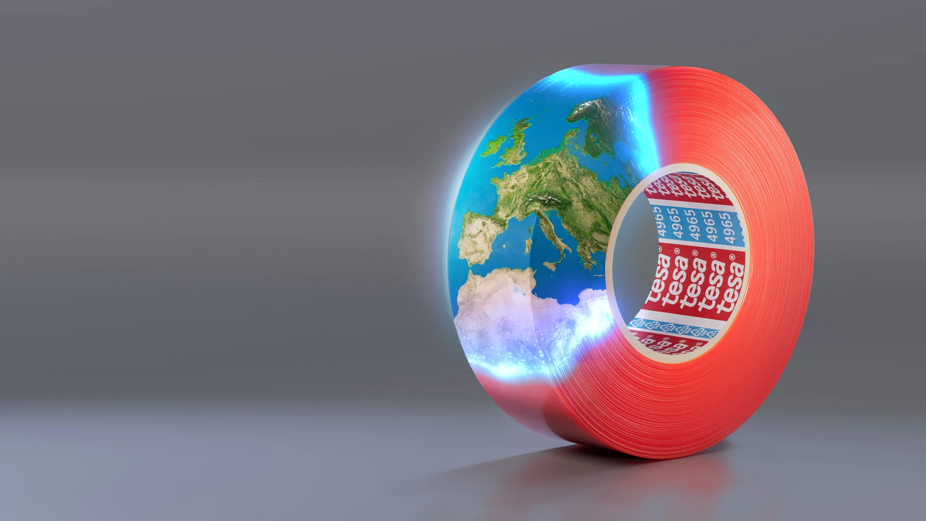 A roll of red adhesive tesa tape with the brand name tesa visible on the inside. The tesa tape is creatively formed into a hollow cylinder containing a section of Earth, depicting Europe and surrounding areas against a gray background. (This text has been generated by AI)