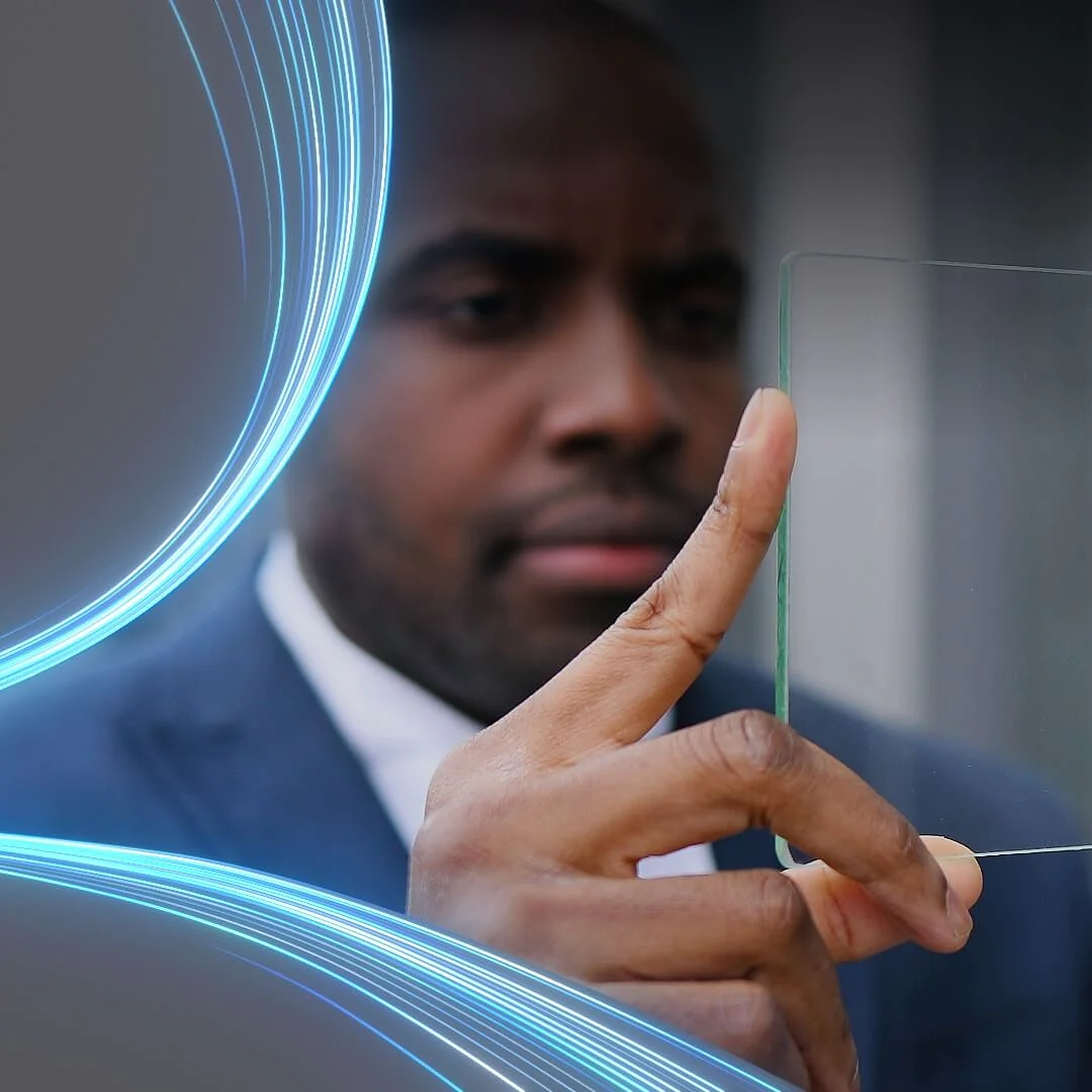 A person in a suit holds a transparent piece of tesa tape between their fingers, examining it closely. Blue glowing lines curve around the left side of the image, adding a futuristic element. (This text has been generated by AI)