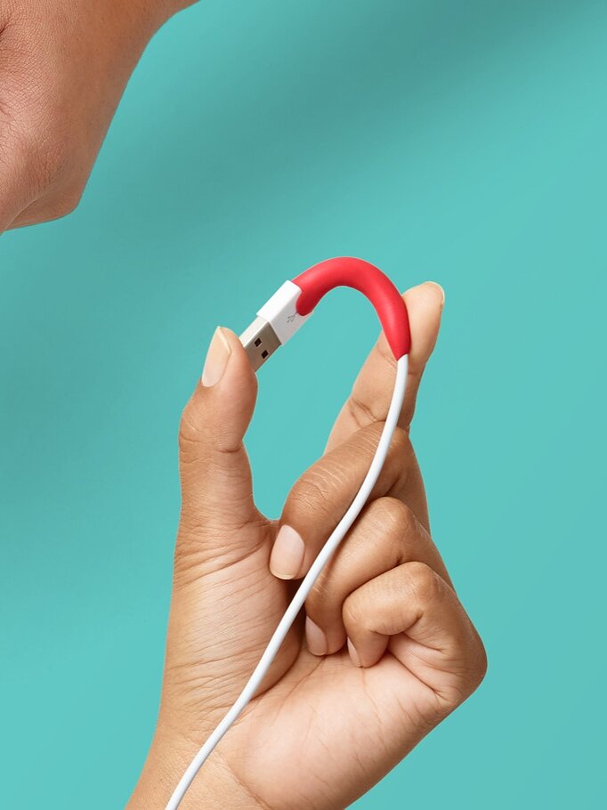 Hands are shown demonstrating the use of red Sugru moldable glue. One image shows it being shaped into a wavy pattern, another shows it wrapped around a cable, and the last image shows it being peeled from its packaging. The background is teal. (This text has been generated by AI)