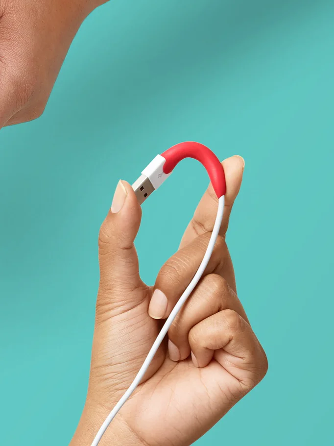 Hands are shown demonstrating the use of red Sugru moldable glue. One image shows it being shaped into a wavy pattern, another shows it wrapped around a cable, and the last image shows it being peeled from its packaging. The background is teal. (This text has been generated by AI)