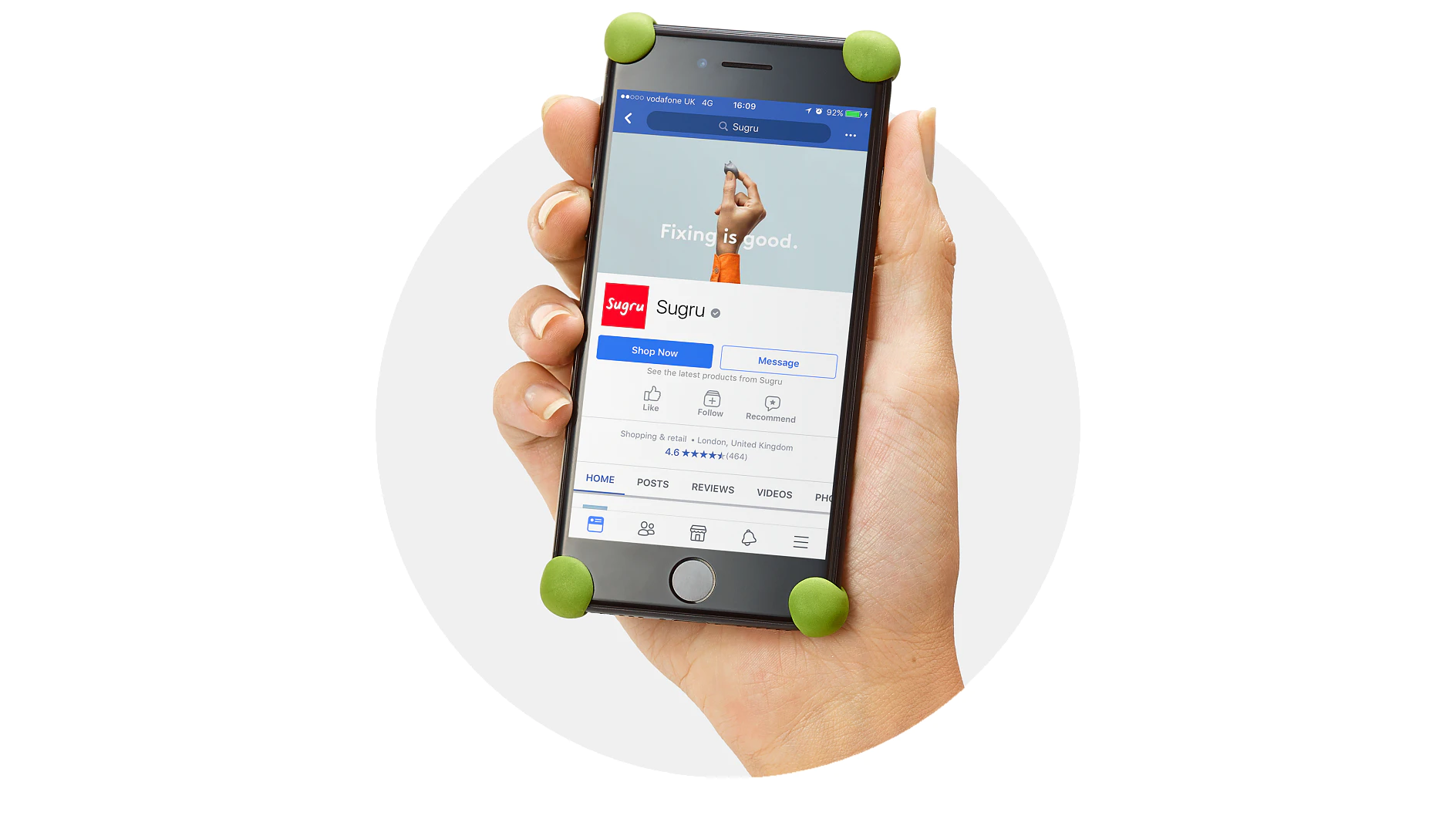A hand holds a smartphone, which displays a Facebook page for Sugru. The phone screen shows the phrase Fixing is good and details about the page. Green Sugru is applied to the phones corners, and the device is against a circular white background. (This text has been generated by AI)