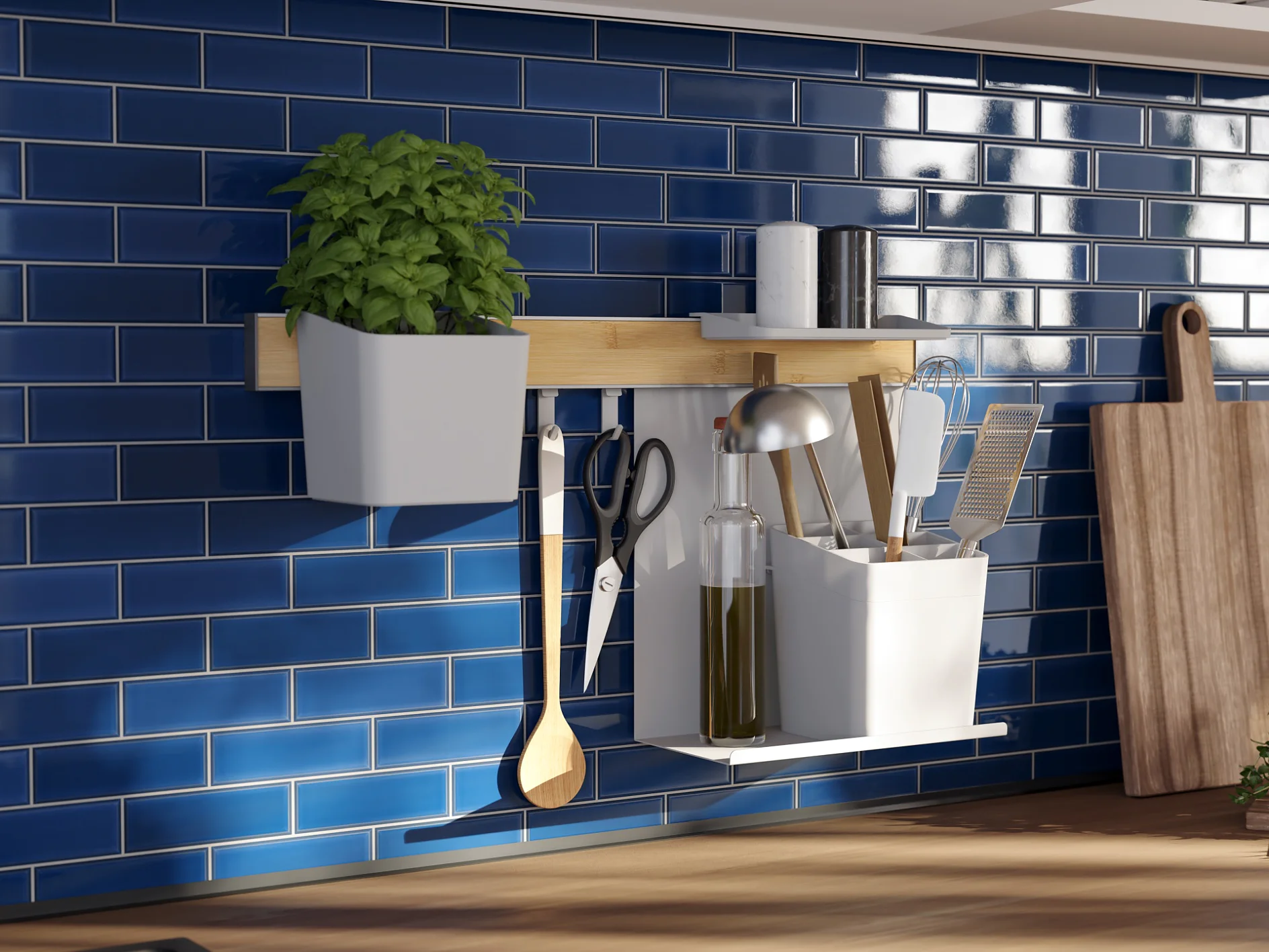 Kitchen counter with blue subway tile backsplash. A wooden shelf holds a potted plant and utensils. Below it, hooks have scissors and a spoon secured with tesa tape. A cutting board, which is also attached using tesa tape, leans against the tile, and a sunny window is visible in the background. (This text has been generated by AI)