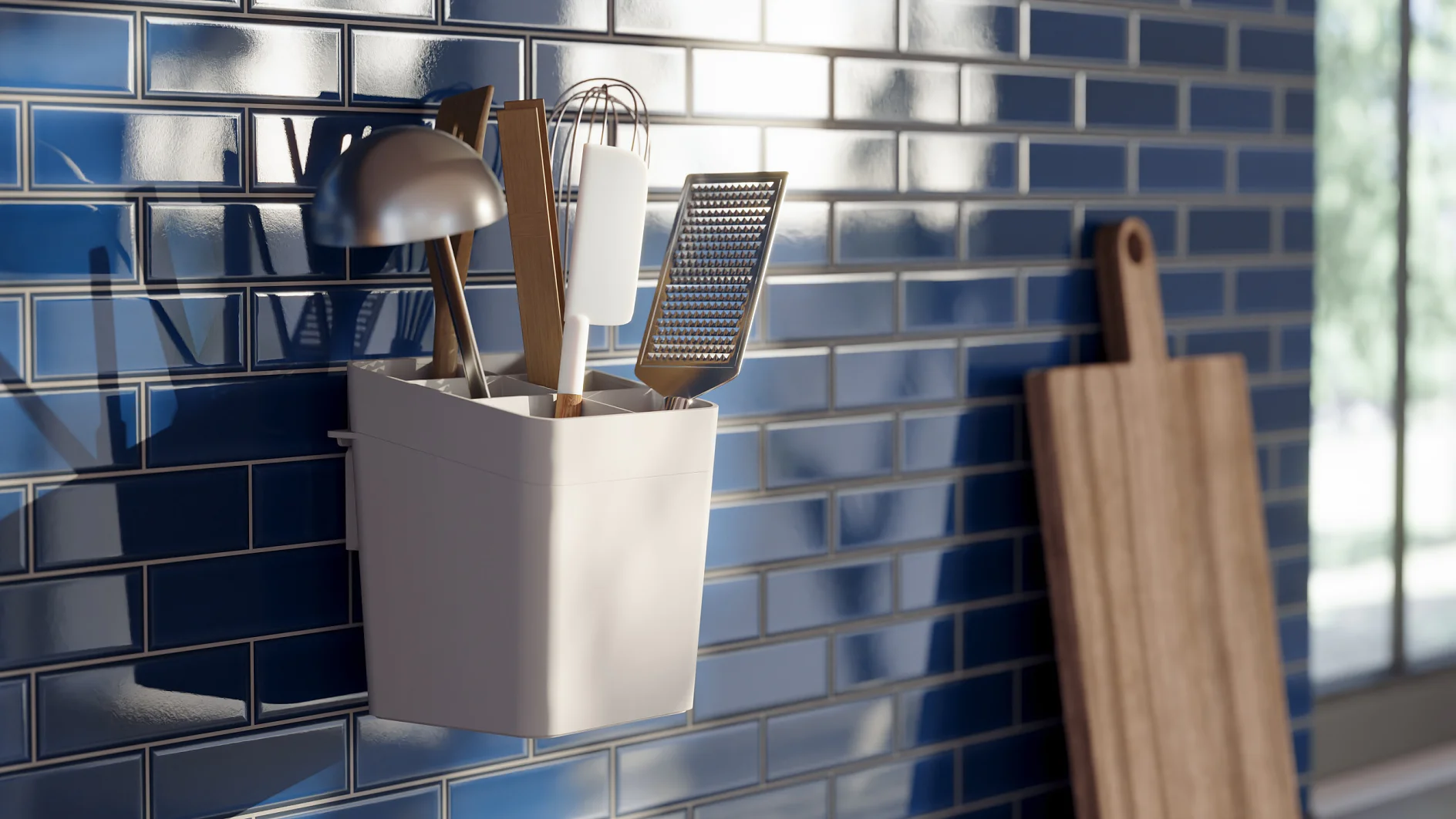 A white container mounted on a blue tiled wall holds kitchen utensils, including a ladle, whisk, spatula, and grater. A wooden cutting board leans against the wall. Sunlight streams in, casting shadows on the tiles. (This text has been generated by AI)