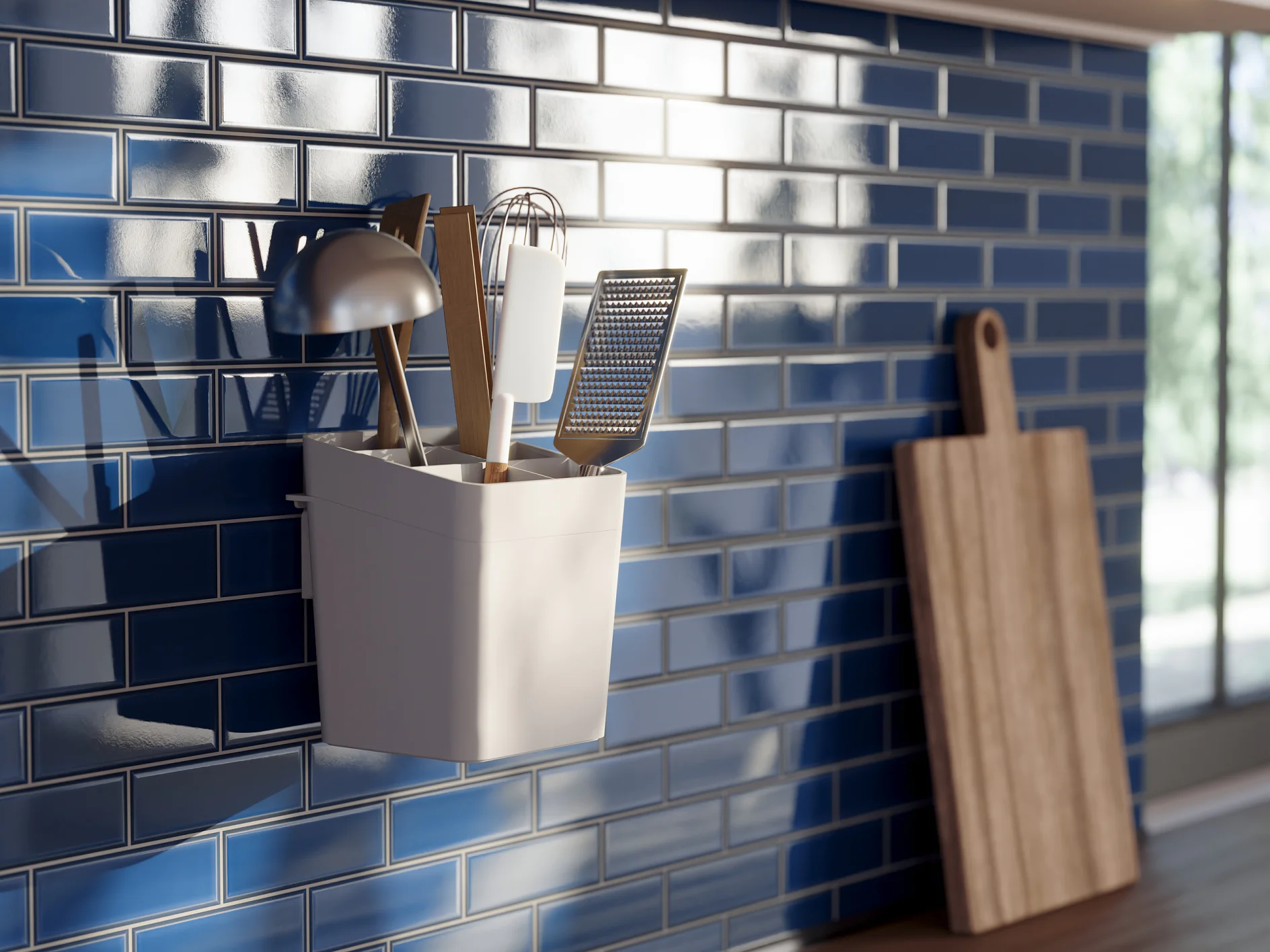 A kitchen scene with a white container holding utensils such as a ladle, spatula, whisk, and grater, mounted on a glossy blue tiled wall using tesa tape. A wooden cutting board leans against the wall to the right. Sunlight casts shadows on the tiles. (This text has been generated by AI)