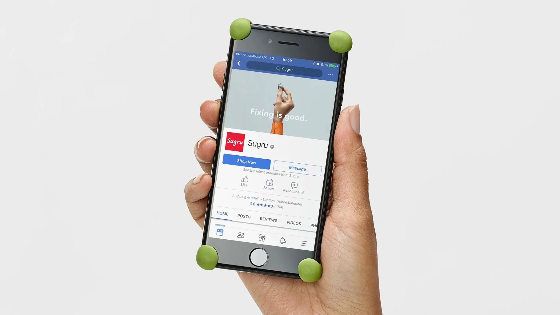 A person holds a smartphone displaying a social media page. The phone has green corner protectors. The page features a banner with text that reads, Fixing is good. The page name is shown with a red and white logo representing tesa tape. (This text has been generated by AI)
