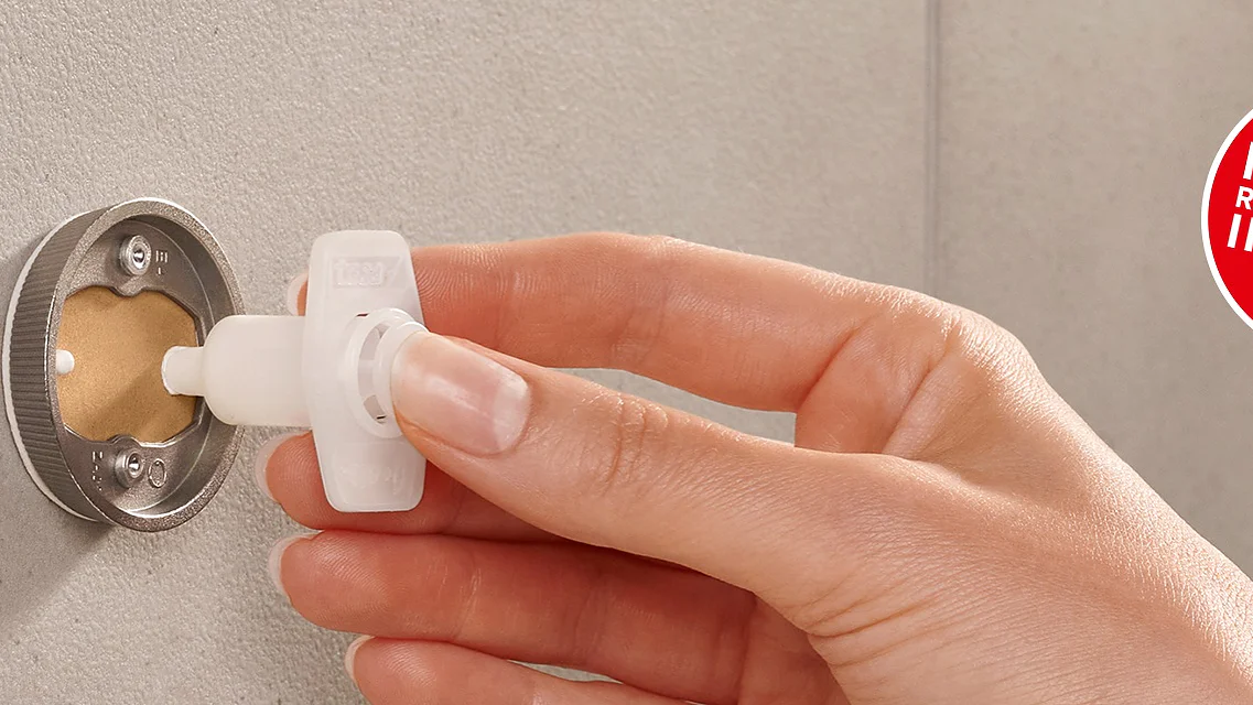 A hand inserts a white plastic plug into a circular opening on a wall. A red circular label on the right reads, Find the right product in 2 min. The wall surface is gray and the plug has a rounded handle. (This text has been generated by AI)
