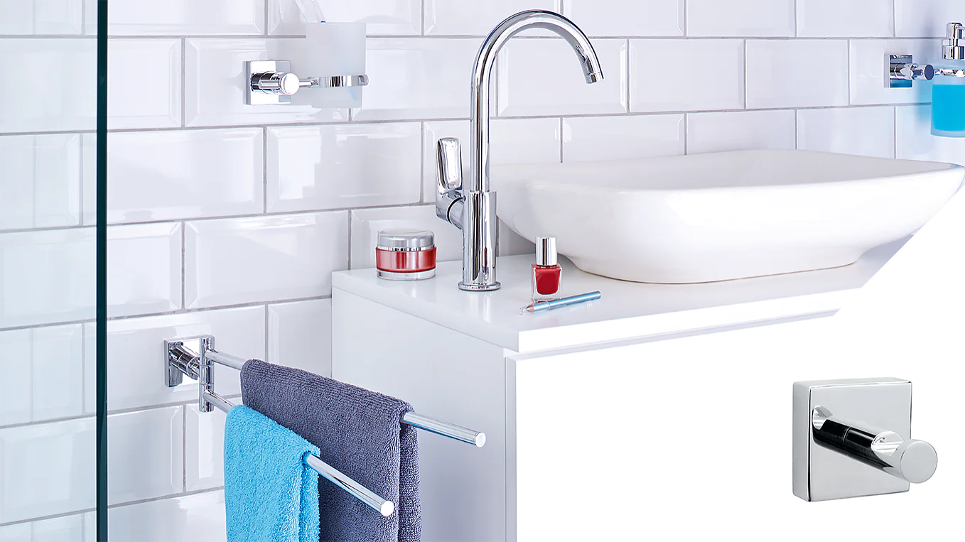A modern bathroom counter with a white rectangular sink, chrome faucet, and accessories including red nail polish and cream jars. A blue towel hangs on a chrome bar. White subway tiles create the wall backdrop. A square hook is inset in the corner using tesa tape. (This text has been generated by AI)