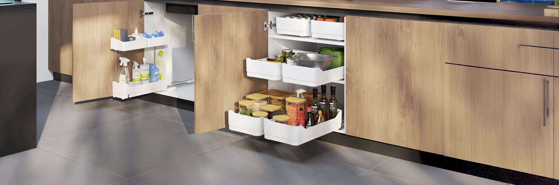 Modern kitchen with wooden cabinets and pull-out shelves. The left cabinet holds cleaning supplies, all neatly organized with the help of tesa tape, while the right has spices, jars, and cookware securely held in place. A blue tile backsplash and countertop with plants and kitchen tools are visible above, where tesa tape can also be used to create a tidy appearance. (This text has been generated by AI)