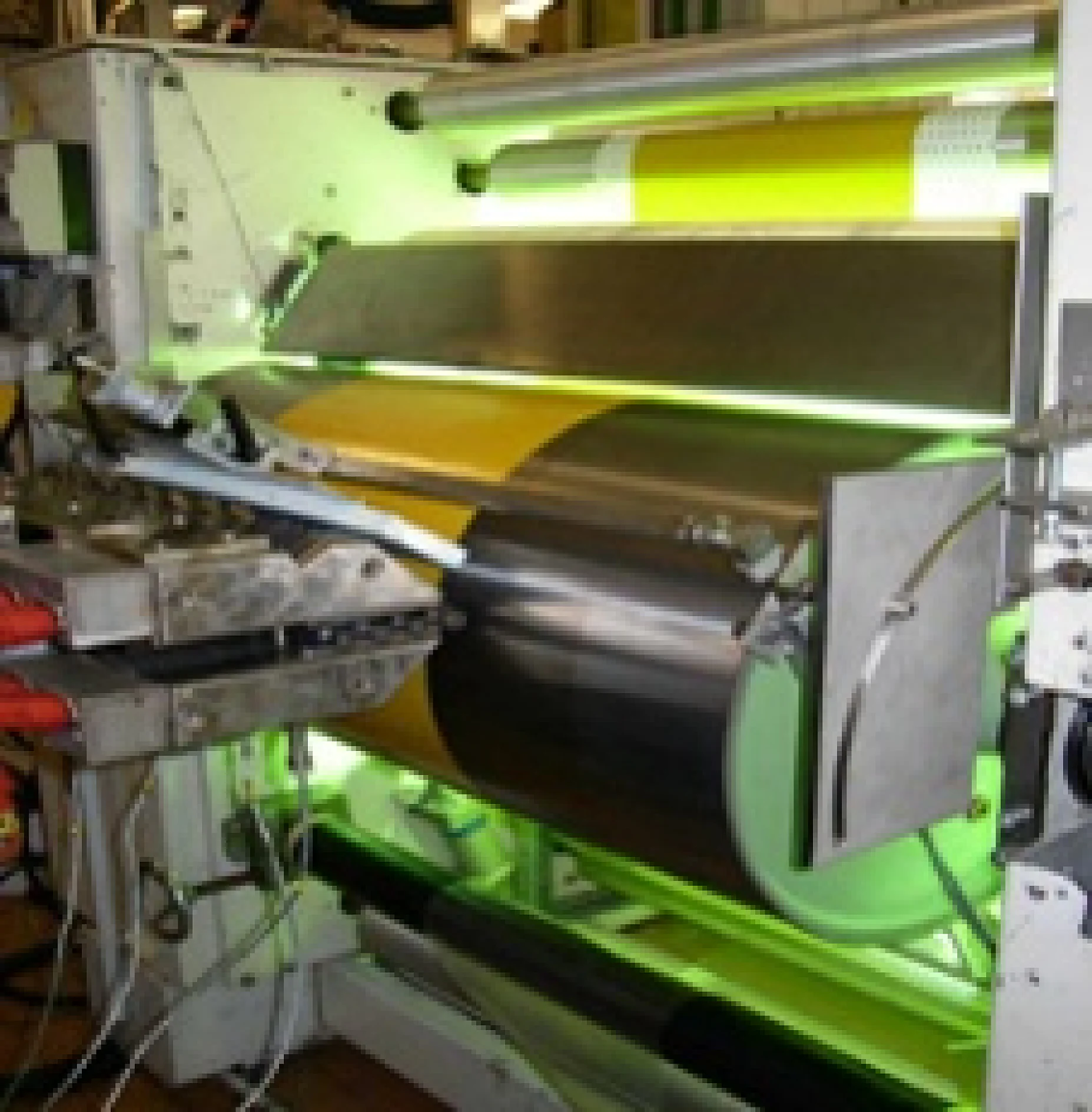 A close-up of an industrial printing press in action shows rollers, machinery parts, and a yellow and black tesa tape section on one roller. (This text has been generated by AI)