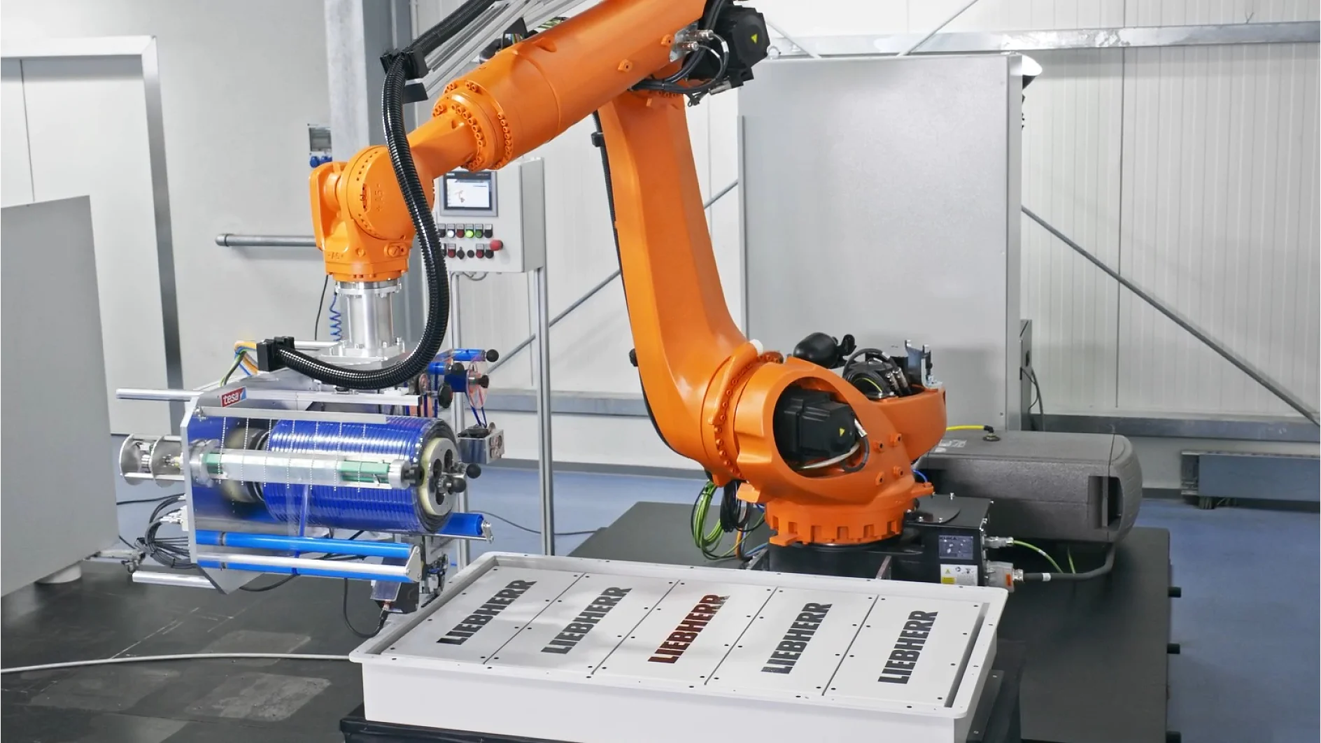 An industrial robotic arm operates above a LIEBHERR table, with tesa tape nearby and machinery and control panels in the background. (This text has been generated by AI)