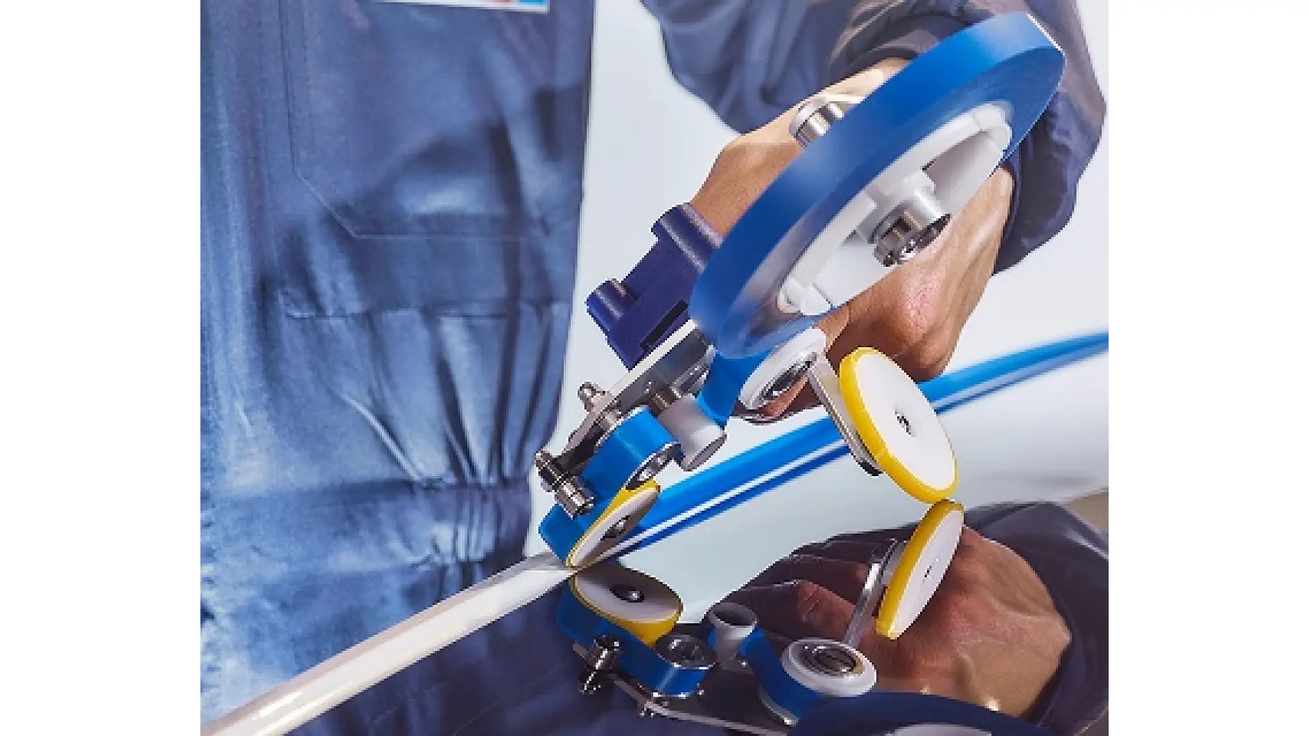 A person in a blue work uniform uses a wheeled precision tool to apply or adjust tesa tape along the edge of a smooth, reflective surface. (This text has been generated by AI)