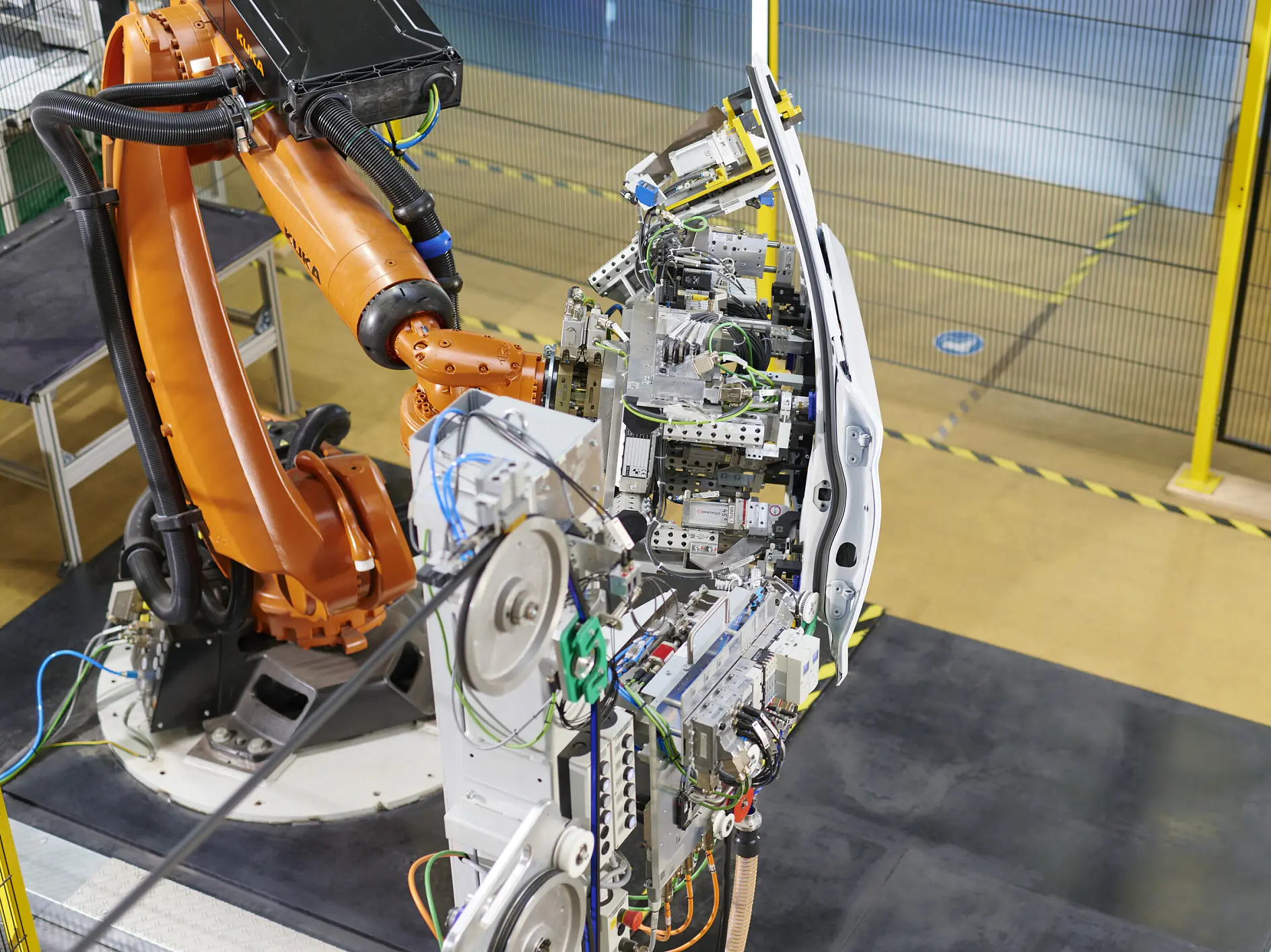industrial robotic arm assembling electronic components on a circuit board in a factory setting with safety barriers visible tesa (This text has been generated by AI)