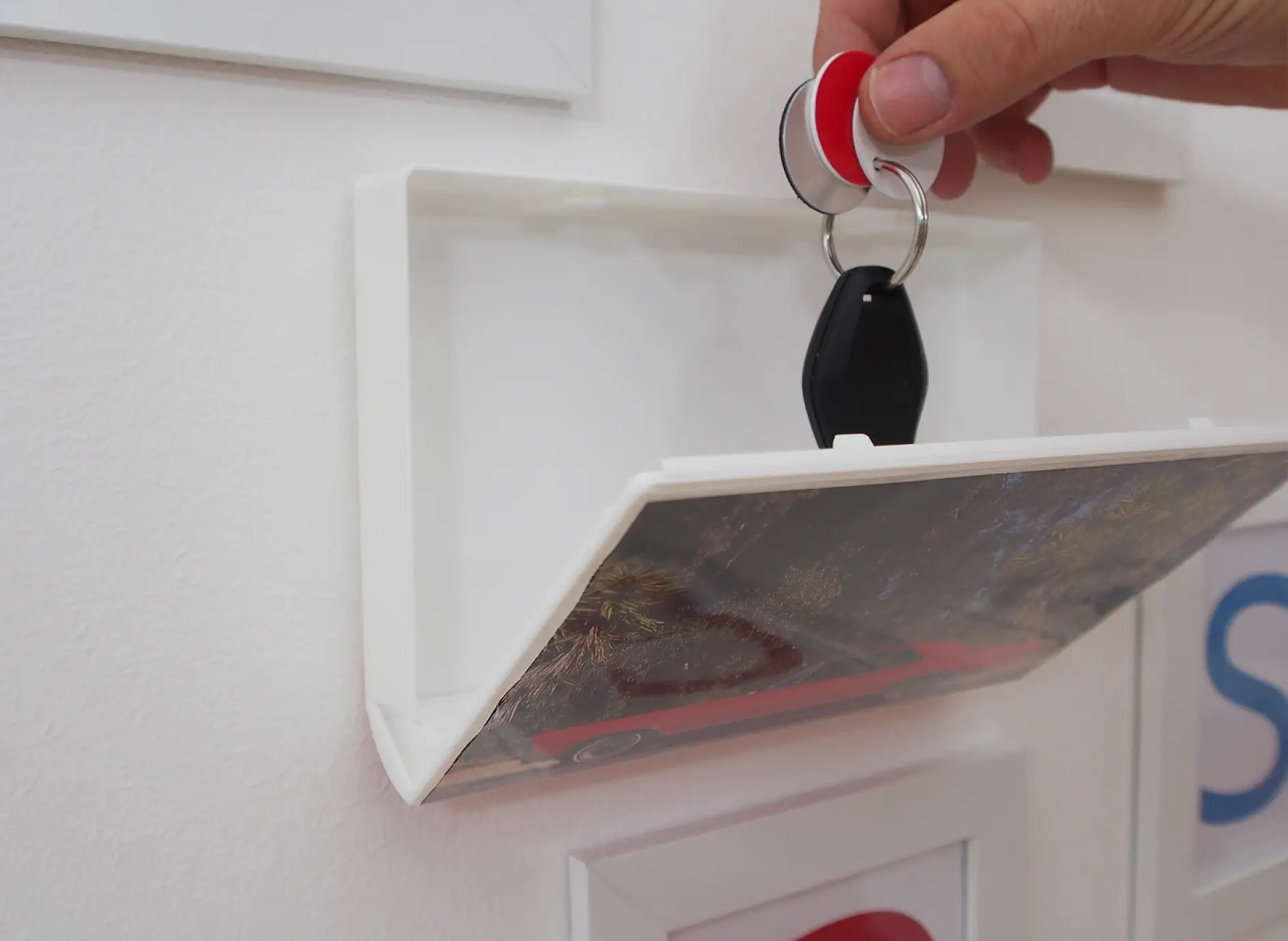 Key being dropped into storage box attached to wall with tesa® Powerbond ULTRA STRONG double-sided adhesive tape