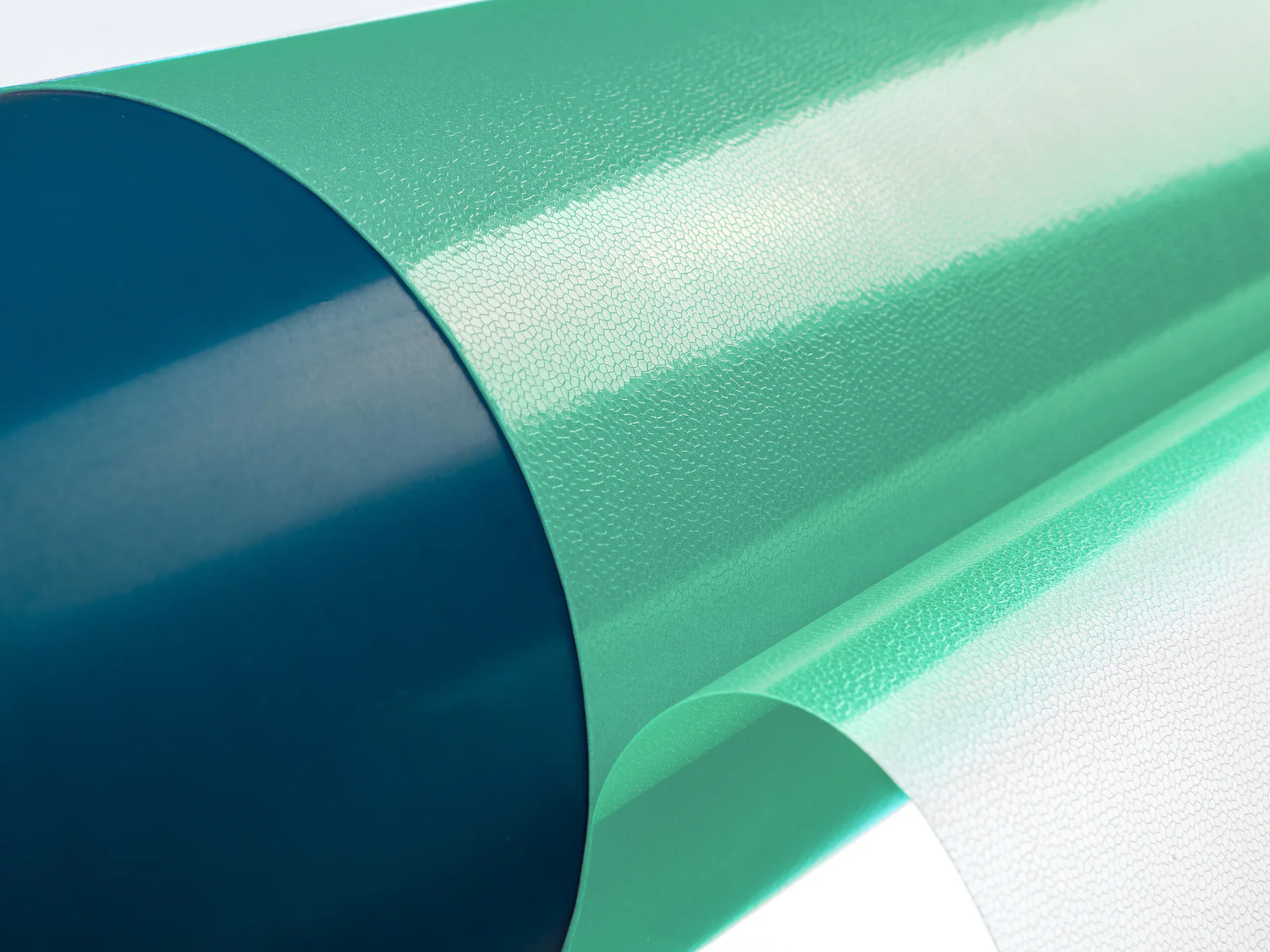 Primer plano de un rollo parcialmente desenrollado de cinta adhesiva verde Tesa con un núcleo azul. La cinta Tesa tiene una superficie brillante y texturizada y está colocada sobre un fondo blanco liso. (This text has been generated by AI)