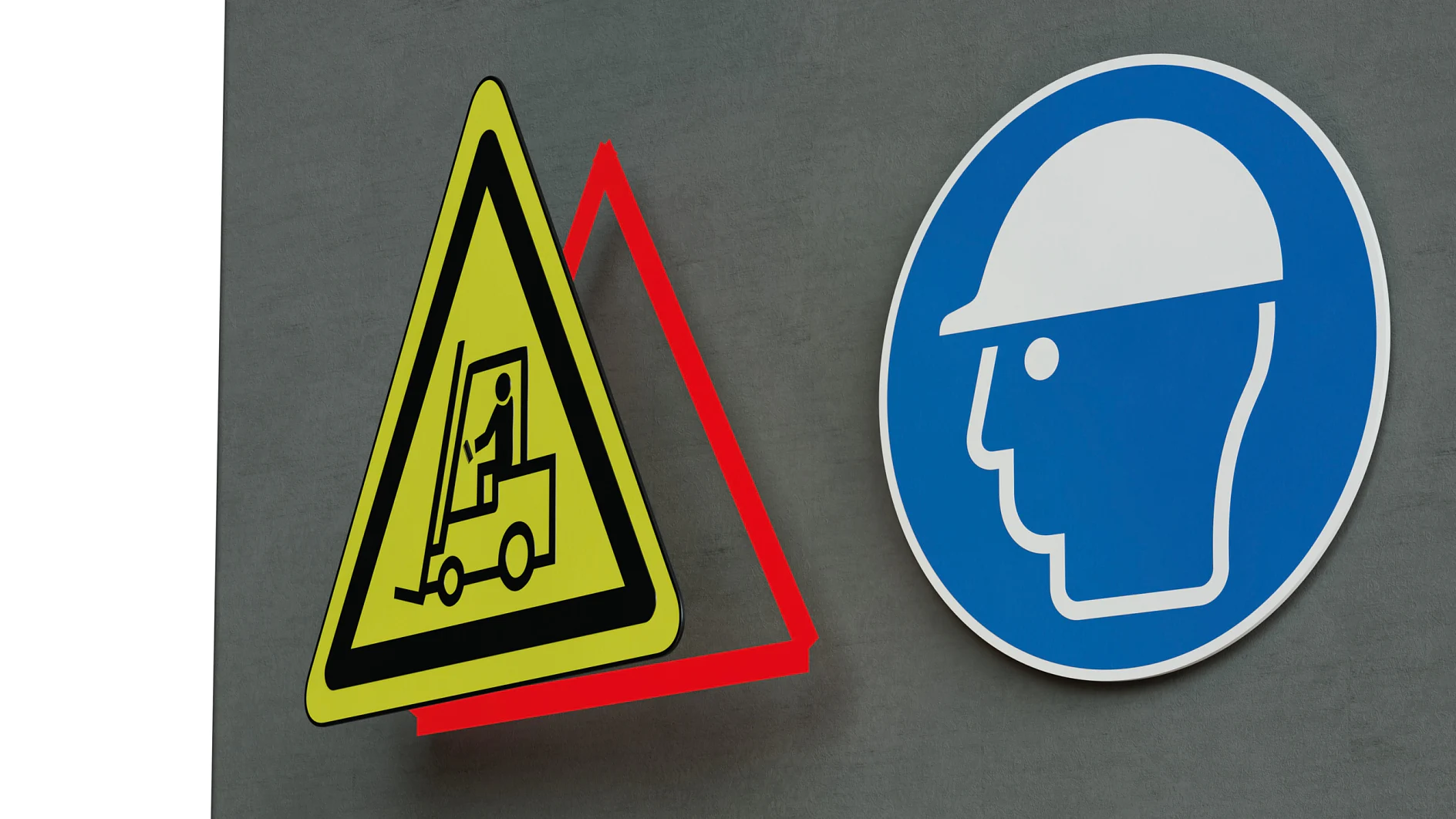 yellow triangular forklift warning sign and blue circular hard hat safety sign mounted on gray wall indoors (This text has been generated by AI)