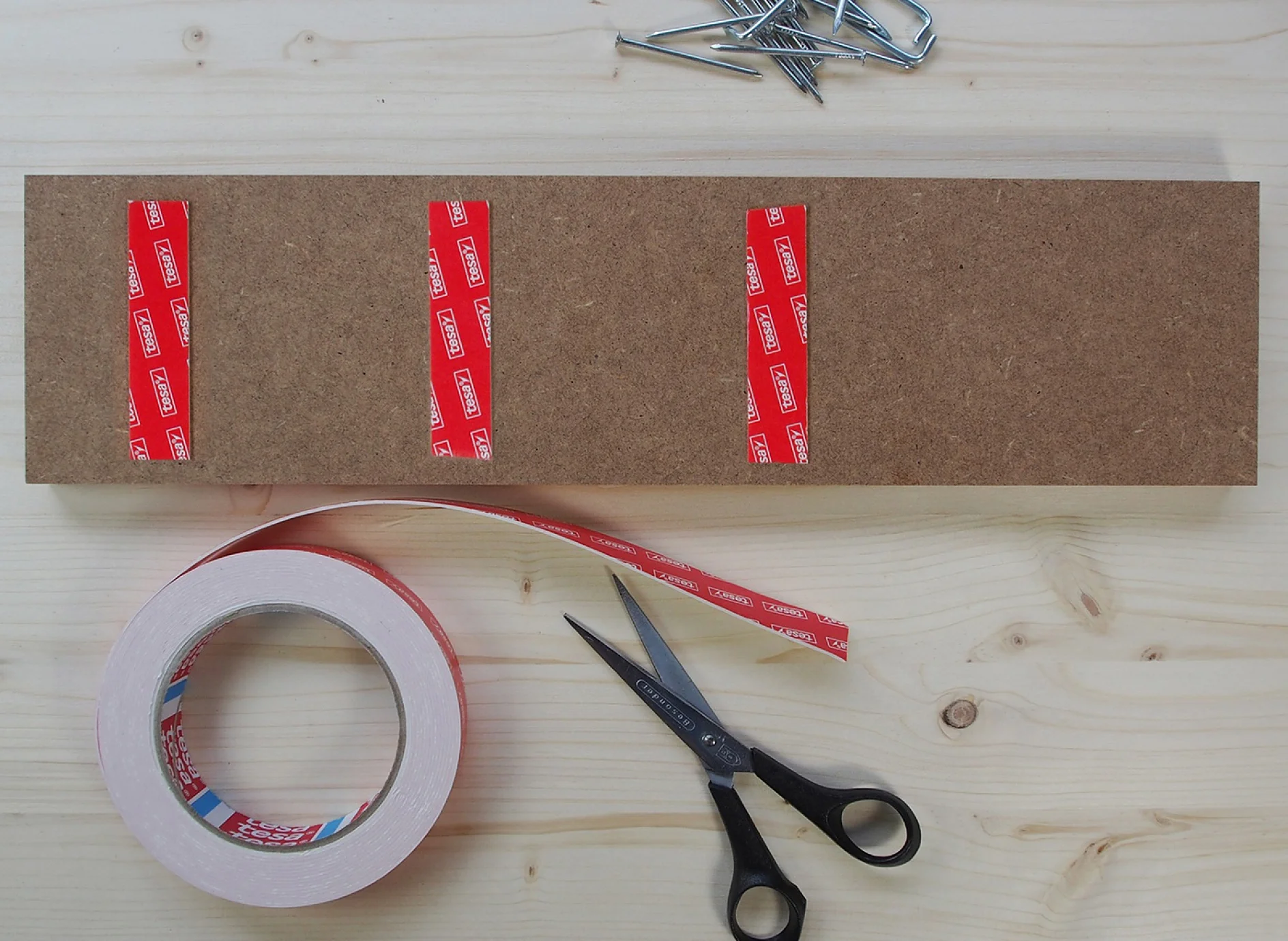 Image of tesa Powerbond® double-sided adhesive tape being applied to MDF.