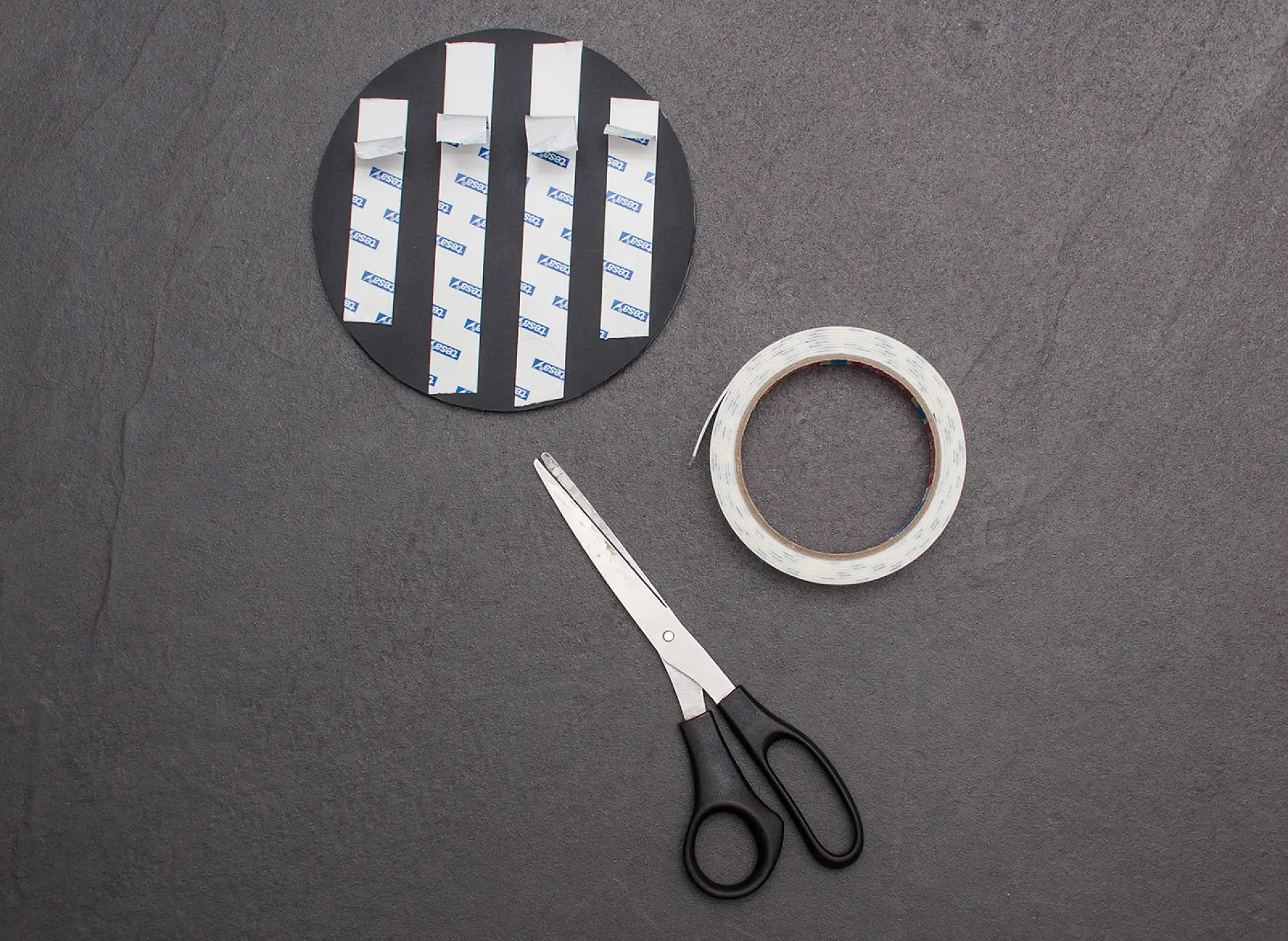 Scissors and four strips of tesa Powerbond® MIRROR adhesive tape applied to reverse of mirror.