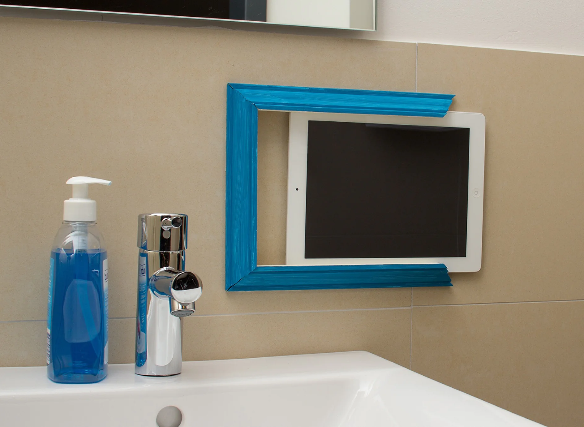 Tablet is pushed into the three U-shaped attached plaster moldings that were attached with tesa Powerbond® MIRROR on the tiles