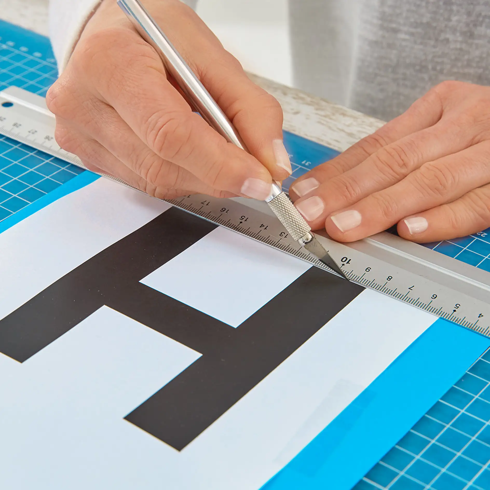 Cutting out the letters using tesa Easy Cut® Desk Dispenser Compact.