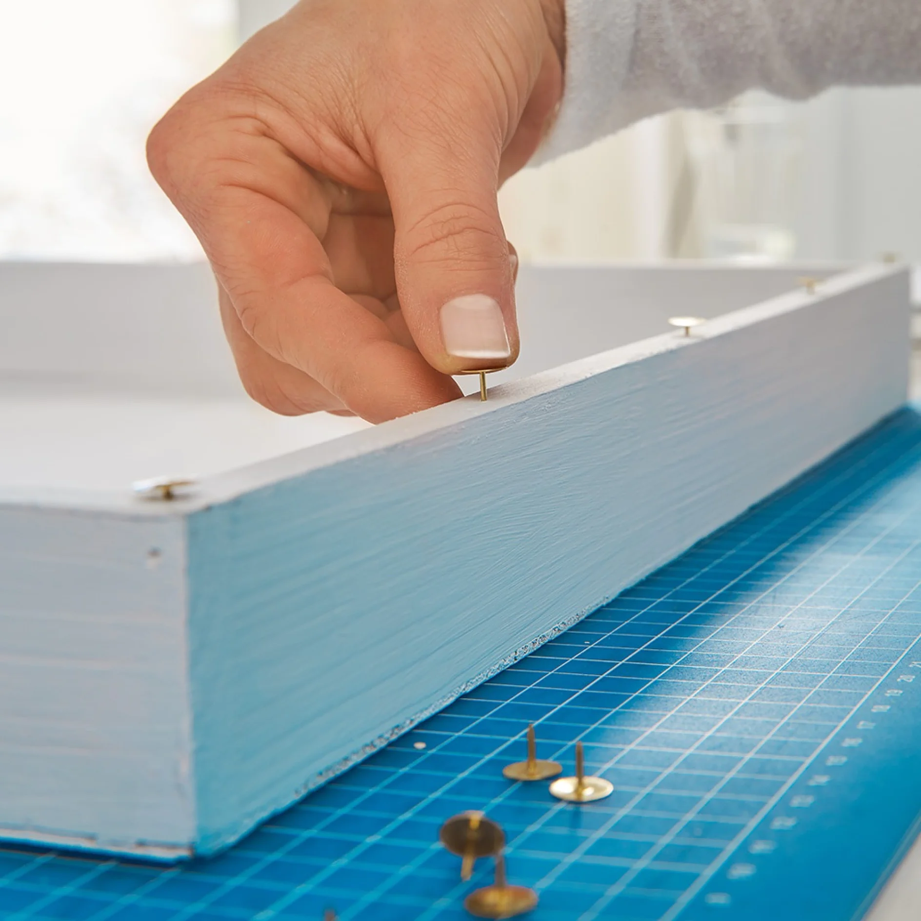 Pressing drawing pins into a tray to create a vertical garden.