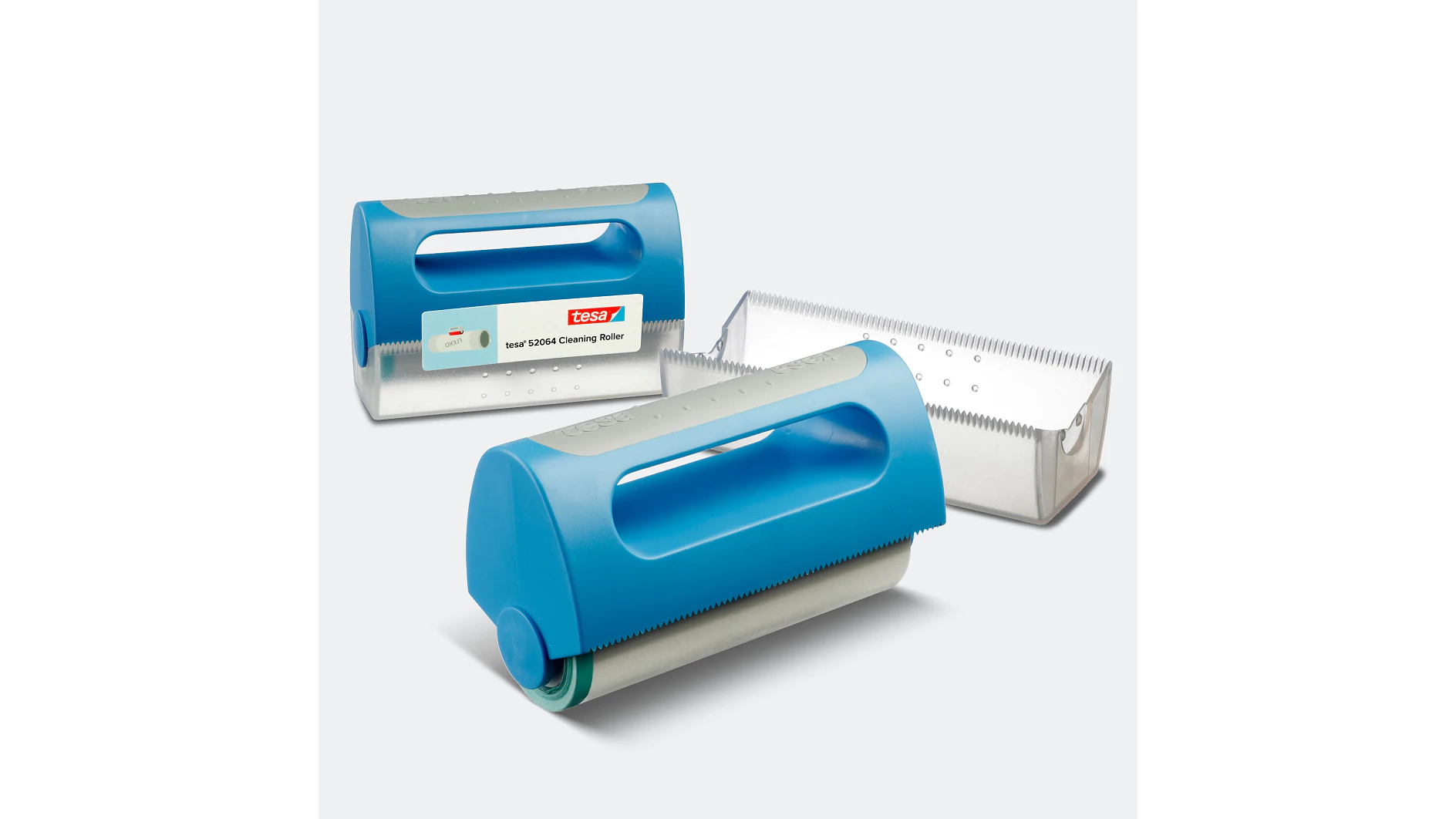 Se muestran tres rodillos limpiadores manuales de color azul con superficies adhesivas de cinta tesa blanca y estuches de plástico gris. Los estuches tienen bordes dentados y uno muestra una etiqueta con la marca. El fondo es liso y de color claro. (This text has been generated by AI)