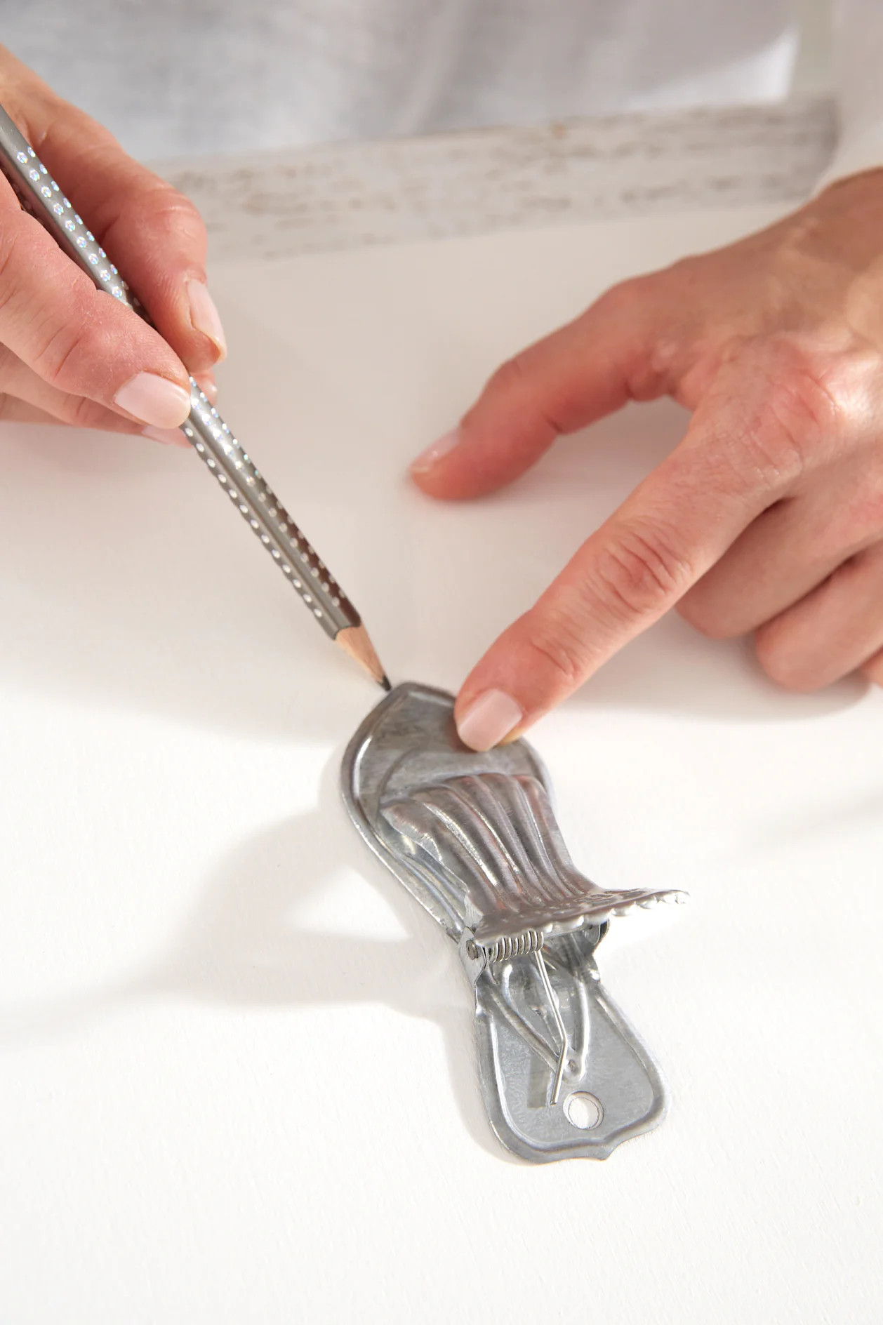 Paint the wooden board with the white varnish on both sides and along the edges. Place the metal clasps and metal hook strips on the board and carefully mark their desired positions with a pencil.