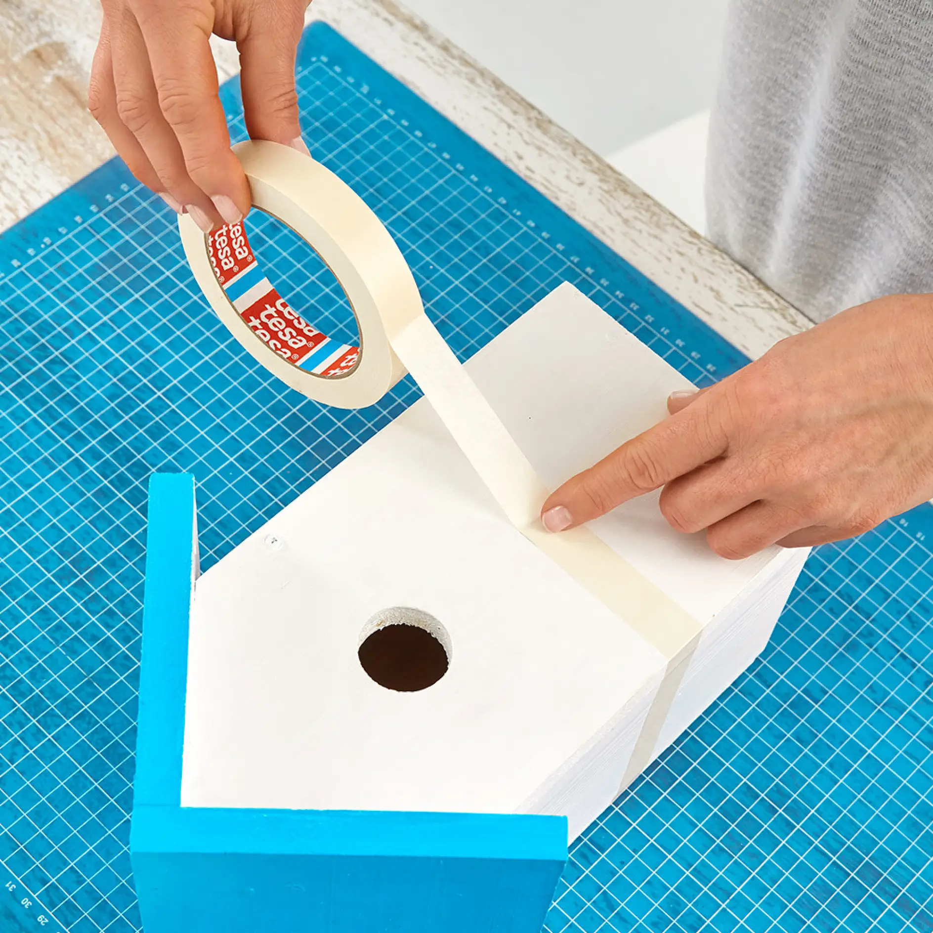Using tesa® Painters Tape PERFECT to mask off a design on wooden bird boxes.