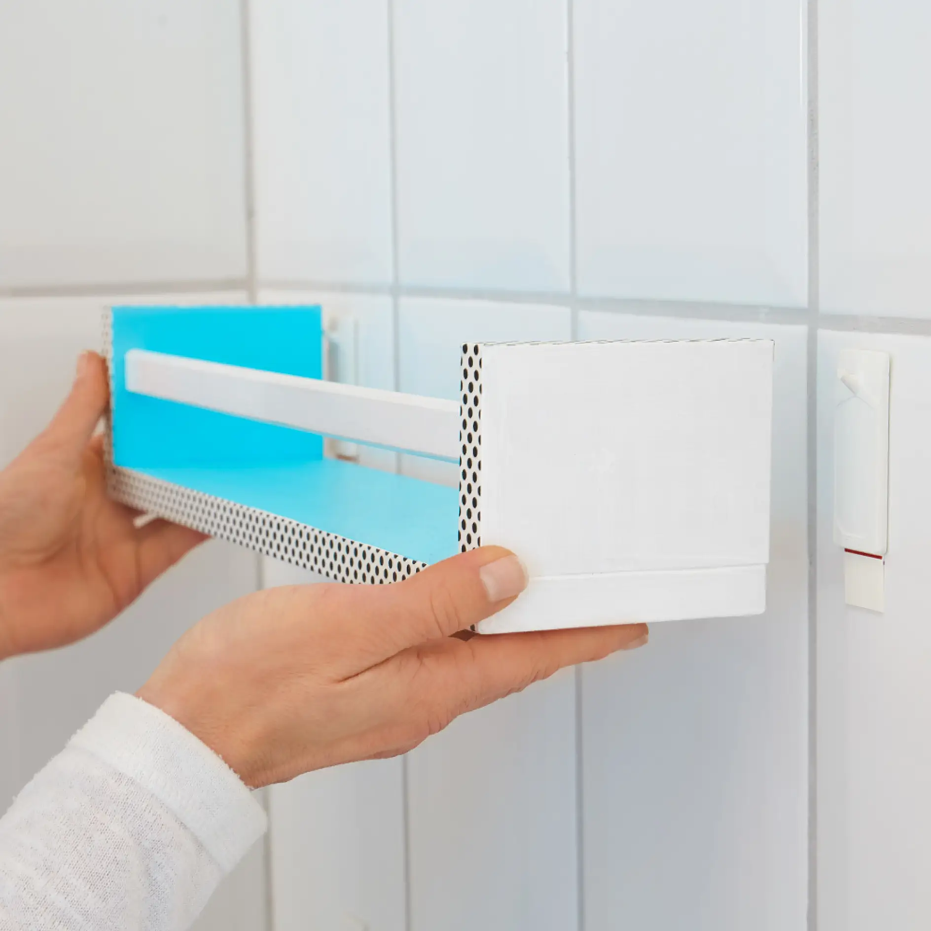 Using tesa® Adhesive Nail for Tiles & Metal 3 kg to wall-mount bathroom shelves – a great bathroom storage idea.