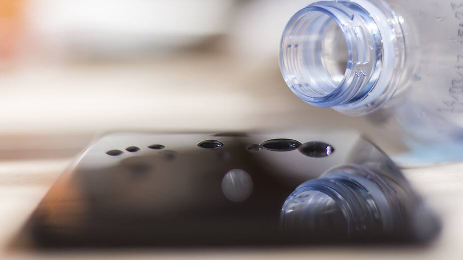 Agua derramada de una botella sobre un smartphone